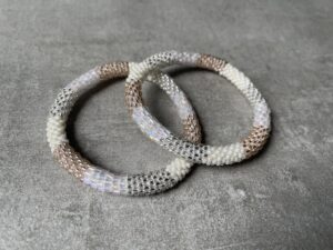 Nepal perle armbånd Nepal armbånd er en inspirerende og fascinerende smykkegenre, der vækker interessen hos smykkeentusiaster over hele verden. Disse håndlavede armbånd er kunstværker, der udstråler autenticitet, skønhed og dyb symbolik. Lad os dykke ned i den betagende verden af Nepal armbånd og udforske, hvad der gør dem så unikke og eftertragtede. Hvert Nepal armbånd er unikt, og det er netop denne individualitet, der appellerer til mange. Armbåndene er ofte skabt af dygtige nepalesiske håndværkere, der gennem generationer har forfinet deres teknikker til at skabe smykker af høj kvalitet. Disse håndværkere bruger traditionelle metoder, som har været en del af Nepals kultur og historie i århundreder. Processen er omhyggelig og kræver en stor grad af præcision og tålmodighed, hvilket gør hvert armbånd til en kærlighedsfyldt skabelse. Nepal armbånd er kendt for deres farverige og levende design. De er ofte dekoreret med perler, ædelstene, træ, metal eller andre naturlige materialer, hvilket giver dem et unikt udseende. Hvert enkelt element, der anvendes i armbåndene, er udvalgt omhyggeligt for at skabe en harmonisk kombination af farver og teksturer. Disse elementer er ofte inspireret af Nepals rige natur og kultur, hvilket giver armbåndene en autentisk følelse og en stærk forbindelse til landet. Symbolik spiller også en vigtig rolle i Nepal armbåndenes popularitet. Mange af armbåndene har indgraverede mønstre eller symboler, der repræsenterer vigtige aspekter af Nepals traditioner og spiritualitet. Disse symboler kan have betydning for held, lykke, kærlighed, beskyttelse eller en dybere forbindelse til naturen. At bære et Nepal armbånd kan derfor have en dybere betydning for bæreren og kan fungere som en påmindelse om deres forbindelse til Nepals rige arv. Nepal armbånd er ikke kun smukke smykker, men de har også en stærk social og kulturel betydning. Mange af disse smykker er håndlavede af kvinder, der er en del af samfundet i landområderne i Nepal. Produktionen af armbåndene giver disse kvinder mulighed for at skabe en bæredygtig indkomst, forbedre deres levevilkår og styrke deres selvstændighed. Når du køber et Nepal armbånd, bidrager du derfor til at støtte en positiv social indvirkning og bevare traditionelle håndværksmæssige metoder. Udover deres kulturelle og sociale betydning er Nepal armbånd også en favorit blandt modebevidste enkeltpersoner, der ønsker at tilføje en unik og autentisk touch til deres stil. Disse armbånd kan styles på utallige måder, uanset om du ønsker at skabe et bohemeinspireret look, en farverig festlig stil eller en subtil og elegant kombination. Der er et Nepal armbånd til enhver lejlighed og enhver personlig præference. I det store udvalg af smykker, der findes i dagens marked, skiller Nepal armbånd sig ud som en særlig perle. Deres håndlavede karakter, farverige design, dybe symbolik og sociale indvirkning gør dem til mere end bare smykker - de er en form for kunst og kultur, der fortæller historien om Nepal og dets folk. Ved at bære et Nepal armbånd, bærer du også med dig en del af dette rige og inspirerende land. Så uanset om du leder efter en meningsfuld gave eller ønsker at berige din egen smykkesamling, vil et Nepal armbånd være et mindeværdigt og værdsat valg.