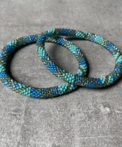 Nepal perle armbånd Nepal armbånd er en inspirerende og fascinerende smykkegenre, der vækker interessen hos smykkeentusiaster over hele verden. Disse håndlavede armbånd er kunstværker, der udstråler autenticitet, skønhed og dyb symbolik. Lad os dykke ned i den betagende verden af Nepal armbånd og udforske, hvad der gør dem så unikke og eftertragtede. Hvert Nepal armbånd er unikt, og det er netop denne individualitet, der appellerer til mange. Armbåndene er ofte skabt af dygtige nepalesiske håndværkere, der gennem generationer har forfinet deres teknikker til at skabe smykker af høj kvalitet. Disse håndværkere bruger traditionelle metoder, som har været en del af Nepals kultur og historie i århundreder. Processen er omhyggelig og kræver en stor grad af præcision og tålmodighed, hvilket gør hvert armbånd til en kærlighedsfyldt skabelse. Nepal armbånd er kendt for deres farverige og levende design. De er ofte dekoreret med perler, ædelstene, træ, metal eller andre naturlige materialer, hvilket giver dem et unikt udseende. Hvert enkelt element, der anvendes i armbåndene, er udvalgt omhyggeligt for at skabe en harmonisk kombination af farver og teksturer. Disse elementer er ofte inspireret af Nepals rige natur og kultur, hvilket giver armbåndene en autentisk følelse og en stærk forbindelse til landet. Symbolik spiller også en vigtig rolle i Nepal armbåndenes popularitet. Mange af armbåndene har indgraverede mønstre eller symboler, der repræsenterer vigtige aspekter af Nepals traditioner og spiritualitet. Disse symboler kan have betydning for held, lykke, kærlighed, beskyttelse eller en dybere forbindelse til naturen. At bære et Nepal armbånd kan derfor have en dybere betydning for bæreren og kan fungere som en påmindelse om deres forbindelse til Nepals rige arv. Nepal armbånd er ikke kun smukke smykker, men de har også en stærk social og kulturel betydning. Mange af disse smykker er håndlavede af kvinder, der er en del af samfundet i landområderne i Nepal. Produktionen af armbåndene giver disse kvinder mulighed for at skabe en bæredygtig indkomst, forbedre deres levevilkår og styrke deres selvstændighed. Når du køber et Nepal armbånd, bidrager du derfor til at støtte en positiv social indvirkning og bevare traditionelle håndværksmæssige metoder. Udover deres kulturelle og sociale betydning er Nepal armbånd også en favorit blandt modebevidste enkeltpersoner, der ønsker at tilføje en unik og autentisk touch til deres stil. Disse armbånd kan styles på utallige måder, uanset om du ønsker at skabe et bohemeinspireret look, en farverig festlig stil eller en subtil og elegant kombination. Der er et Nepal armbånd til enhver lejlighed og enhver personlig præference. I det store udvalg af smykker, der findes i dagens marked, skiller Nepal armbånd sig ud som en særlig perle. Deres håndlavede karakter, farverige design, dybe symbolik og sociale indvirkning gør dem til mere end bare smykker - de er en form for kunst og kultur, der fortæller historien om Nepal og dets folk. Ved at bære et Nepal armbånd, bærer du også med dig en del af dette rige og inspirerende land. Så uanset om du leder efter en meningsfuld gave eller ønsker at berige din egen smykkesamling, vil et Nepal armbånd være et mindeværdigt og værdsat valg.