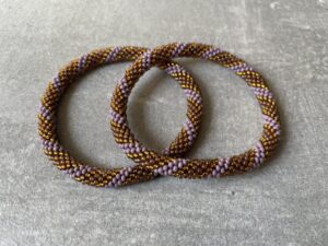 Nepal armbånd er en inspirerende og fascinerende smykkegenre, der vækker interessen hos smykkeentusiaster over hele verden. Disse håndlavede armbånd er kunstværker, der udstråler autenticitet, skønhed og dyb symbolik. Lad os dykke ned i den betagende verden af Nepal armbånd og udforske, hvad der gør dem så unikke og eftertragtede. Hvert Nepal armbånd er unikt, og det er netop denne individualitet, der appellerer til mange. Armbåndene er ofte skabt af dygtige nepalesiske håndværkere, der gennem generationer har forfinet deres teknikker til at skabe smykker af høj kvalitet. Disse håndværkere bruger traditionelle metoder, som har været en del af Nepals kultur og historie i århundreder. Processen er omhyggelig og kræver en stor grad af præcision og tålmodighed, hvilket gør hvert armbånd til en kærlighedsfyldt skabelse. Nepal armbånd er kendt for deres farverige og levende design. De er ofte dekoreret med perler, ædelstene, træ, metal eller andre naturlige materialer, hvilket giver dem et unikt udseende. Hvert enkelt element, der anvendes i armbåndene, er udvalgt omhyggeligt for at skabe en harmonisk kombination af farver og teksturer. Disse elementer er ofte inspireret af Nepals rige natur og kultur, hvilket giver armbåndene en autentisk følelse og en stærk forbindelse til landet. Symbolik spiller også en vigtig rolle i Nepal armbåndenes popularitet. Mange af armbåndene har indgraverede mønstre eller symboler, der repræsenterer vigtige aspekter af Nepals traditioner og spiritualitet. Disse symboler kan have betydning for held, lykke, kærlighed, beskyttelse eller en dybere forbindelse til naturen. At bære et Nepal armbånd kan derfor have en dybere betydning for bæreren og kan fungere som en påmindelse om deres forbindelse til Nepals rige arv. Nepal armbånd er ikke kun smukke smykker, men de har også en stærk social og kulturel betydning. Mange af disse smykker er håndlavede af kvinder, der er en del af samfundet i landområderne i Nepal. Produktionen af armbåndene giver disse kvinder mulighed for at skabe en bæredygtig indkomst, forbedre deres levevilkår og styrke deres selvstændighed. Når du køber et Nepal armbånd, bidrager du derfor til at støtte en positiv social indvirkning og bevare traditionelle håndværksmæssige metoder. Udover deres kulturelle og sociale betydning er Nepal armbånd også en favorit blandt modebevidste enkeltpersoner, der ønsker at tilføje en unik og autentisk touch til deres stil. Disse armbånd kan styles på utallige måder, uanset om du ønsker at skabe et bohemeinspireret look, en farverig festlig stil eller en subtil og elegant kombination. Der er et Nepal armbånd til enhver lejlighed og enhver personlig præference. I det store udvalg af smykker, der findes i dagens marked, skiller Nepal armbånd sig ud som en særlig perle. Deres håndlavede karakter, farverige design, dybe symbolik og sociale indvirkning gør dem til mere end bare smykker - de er en form for kunst og kultur, der fortæller historien om Nepal og dets folk. Ved at bære et Nepal armbånd, bærer du også med dig en del af dette rige og inspirerende land. Så uanset om du leder efter en meningsfuld gave eller ønsker at berige din egen smykkesamling, vil et Nepal armbånd være et mindeværdigt og værdsat valg.