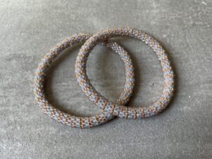 Nepal armbånd er en inspirerende og fascinerende smykkegenre, der vækker interessen hos smykkeentusiaster over hele verden. Disse håndlavede armbånd er kunstværker, der udstråler autenticitet, skønhed og dyb symbolik. Lad os dykke ned i den betagende verden af Nepal armbånd og udforske, hvad der gør dem så unikke og eftertragtede. Hvert Nepal armbånd er unikt, og det er netop denne individualitet, der appellerer til mange. Armbåndene er ofte skabt af dygtige nepalesiske håndværkere, der gennem generationer har forfinet deres teknikker til at skabe smykker af høj kvalitet. Disse håndværkere bruger traditionelle metoder, som har været en del af Nepals kultur og historie i århundreder. Processen er omhyggelig og kræver en stor grad af præcision og tålmodighed, hvilket gør hvert armbånd til en kærlighedsfyldt skabelse. Nepal armbånd er kendt for deres farverige og levende design. De er ofte dekoreret med perler, ædelstene, træ, metal eller andre naturlige materialer, hvilket giver dem et unikt udseende. Hvert enkelt element, der anvendes i armbåndene, er udvalgt omhyggeligt for at skabe en harmonisk kombination af farver og teksturer. Disse elementer er ofte inspireret af Nepals rige natur og kultur, hvilket giver armbåndene en autentisk følelse og en stærk forbindelse til landet. Symbolik spiller også en vigtig rolle i Nepal armbåndenes popularitet. Mange af armbåndene har indgraverede mønstre eller symboler, der repræsenterer vigtige aspekter af Nepals traditioner og spiritualitet. Disse symboler kan have betydning for held, lykke, kærlighed, beskyttelse eller en dybere forbindelse til naturen. At bære et Nepal armbånd kan derfor have en dybere betydning for bæreren og kan fungere som en påmindelse om deres forbindelse til Nepals rige arv. Nepal armbånd er ikke kun smukke smykker, men de har også en stærk social og kulturel betydning. Mange af disse smykker er håndlavede af kvinder, der er en del af samfundet i landområderne i Nepal. Produktionen af armbåndene giver disse kvinder mulighed for at skabe en bæredygtig indkomst, forbedre deres levevilkår og styrke deres selvstændighed. Når du køber et Nepal armbånd, bidrager du derfor til at støtte en positiv social indvirkning og bevare traditionelle håndværksmæssige metoder. Udover deres kulturelle og sociale betydning er Nepal armbånd også en favorit blandt modebevidste enkeltpersoner, der ønsker at tilføje en unik og autentisk touch til deres stil. Disse armbånd kan styles på utallige måder, uanset om du ønsker at skabe et bohemeinspireret look, en farverig festlig stil eller en subtil og elegant kombination. Der er et Nepal armbånd til enhver lejlighed og enhver personlig præference. I det store udvalg af smykker, der findes i dagens marked, skiller Nepal armbånd sig ud som en særlig perle. Deres håndlavede karakter, farverige design, dybe symbolik og sociale indvirkning gør dem til mere end bare smykker - de er en form for kunst og kultur, der fortæller historien om Nepal og dets folk. Ved at bære et Nepal armbånd, bærer du også med dig en del af dette rige og inspirerende land. Så uanset om du leder efter en meningsfuld gave eller ønsker at berige din egen smykkesamling, vil et Nepal armbånd være et mindeværdigt og værdsat valg.