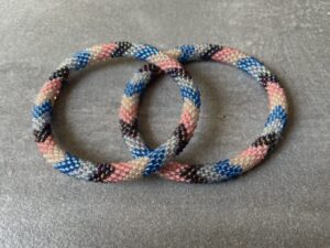 Nepal armbånd er en inspirerende og fascinerende smykkegenre, der vækker interessen hos smykkeentusiaster over hele verden. Disse håndlavede armbånd er kunstværker, der udstråler autenticitet, skønhed og dyb symbolik. Lad os dykke ned i den betagende verden af Nepal armbånd og udforske, hvad der gør dem så unikke og eftertragtede. Hvert Nepal armbånd er unikt, og det er netop denne individualitet, der appellerer til mange. Armbåndene er ofte skabt af dygtige nepalesiske håndværkere, der gennem generationer har forfinet deres teknikker til at skabe smykker af høj kvalitet. Disse håndværkere bruger traditionelle metoder, som har været en del af Nepals kultur og historie i århundreder. Processen er omhyggelig og kræver en stor grad af præcision og tålmodighed, hvilket gør hvert armbånd til en kærlighedsfyldt skabelse. Nepal armbånd er kendt for deres farverige og levende design. De er ofte dekoreret med perler, ædelstene, træ, metal eller andre naturlige materialer, hvilket giver dem et unikt udseende. Hvert enkelt element, der anvendes i armbåndene, er udvalgt omhyggeligt for at skabe en harmonisk kombination af farver og teksturer. Disse elementer er ofte inspireret af Nepals rige natur og kultur, hvilket giver armbåndene en autentisk følelse og en stærk forbindelse til landet. Symbolik spiller også en vigtig rolle i Nepal armbåndenes popularitet. Mange af armbåndene har indgraverede mønstre eller symboler, der repræsenterer vigtige aspekter af Nepals traditioner og spiritualitet. Disse symboler kan have betydning for held, lykke, kærlighed, beskyttelse eller en dybere forbindelse til naturen. At bære et Nepal armbånd kan derfor have en dybere betydning for bæreren og kan fungere som en påmindelse om deres forbindelse til Nepals rige arv. Nepal armbånd er ikke kun smukke smykker, men de har også en stærk social og kulturel betydning. Mange af disse smykker er håndlavede af kvinder, der er en del af samfundet i landområderne i Nepal. Produktionen af armbåndene giver disse kvinder mulighed for at skabe en bæredygtig indkomst, forbedre deres levevilkår og styrke deres selvstændighed. Når du køber et Nepal armbånd, bidrager du derfor til at støtte en positiv social indvirkning og bevare traditionelle håndværksmæssige metoder. Udover deres kulturelle og sociale betydning er Nepal armbånd også en favorit blandt modebevidste enkeltpersoner, der ønsker at tilføje en unik og autentisk touch til deres stil. Disse armbånd kan styles på utallige måder, uanset om du ønsker at skabe et bohemeinspireret look, en farverig festlig stil eller en subtil og elegant kombination. Der er et Nepal armbånd til enhver lejlighed og enhver personlig præference. I det store udvalg af smykker, der findes i dagens marked, skiller Nepal armbånd sig ud som en særlig perle. Deres håndlavede karakter, farverige design, dybe symbolik og sociale indvirkning gør dem til mere end bare smykker - de er en form for kunst og kultur, der fortæller historien om Nepal og dets folk. Ved at bære et Nepal armbånd, bærer du også med dig en del af dette rige og inspirerende land. Så uanset om du leder efter en meningsfuld gave eller ønsker at berige din egen smykkesamling, vil et Nepal armbånd være et mindeværdigt og værdsat valg.