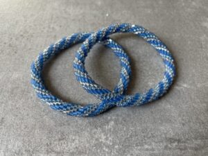 Nepal armbånd er en inspirerende og fascinerende smykkegenre, der vækker interessen hos smykkeentusiaster over hele verden. Disse håndlavede armbånd er kunstværker, der udstråler autenticitet, skønhed og dyb symbolik. Lad os dykke ned i den betagende verden af Nepal armbånd og udforske, hvad der gør dem så unikke og eftertragtede. Hvert Nepal armbånd er unikt, og det er netop denne individualitet, der appellerer til mange. Armbåndene er ofte skabt af dygtige nepalesiske håndværkere, der gennem generationer har forfinet deres teknikker til at skabe smykker af høj kvalitet. Disse håndværkere bruger traditionelle metoder, som har været en del af Nepals kultur og historie i århundreder. Processen er omhyggelig og kræver en stor grad af præcision og tålmodighed, hvilket gør hvert armbånd til en kærlighedsfyldt skabelse. Nepal armbånd er kendt for deres farverige og levende design. De er ofte dekoreret med perler, ædelstene, træ, metal eller andre naturlige materialer, hvilket giver dem et unikt udseende. Hvert enkelt element, der anvendes i armbåndene, er udvalgt omhyggeligt for at skabe en harmonisk kombination af farver og teksturer. Disse elementer er ofte inspireret af Nepals rige natur og kultur, hvilket giver armbåndene en autentisk følelse og en stærk forbindelse til landet. Symbolik spiller også en vigtig rolle i Nepal armbåndenes popularitet. Mange af armbåndene har indgraverede mønstre eller symboler, der repræsenterer vigtige aspekter af Nepals traditioner og spiritualitet. Disse symboler kan have betydning for held, lykke, kærlighed, beskyttelse eller en dybere forbindelse til naturen. At bære et Nepal armbånd kan derfor have en dybere betydning for bæreren og kan fungere som en påmindelse om deres forbindelse til Nepals rige arv. Nepal armbånd er ikke kun smukke smykker, men de har også en stærk social og kulturel betydning. Mange af disse smykker er håndlavede af kvinder, der er en del af samfundet i landområderne i Nepal. Produktionen af armbåndene giver disse kvinder mulighed for at skabe en bæredygtig indkomst, forbedre deres levevilkår og styrke deres selvstændighed. Når du køber et Nepal armbånd, bidrager du derfor til at støtte en positiv social indvirkning og bevare traditionelle håndværksmæssige metoder. Udover deres kulturelle og sociale betydning er Nepal armbånd også en favorit blandt modebevidste enkeltpersoner, der ønsker at tilføje en unik og autentisk touch til deres stil. Disse armbånd kan styles på utallige måder, uanset om du ønsker at skabe et bohemeinspireret look, en farverig festlig stil eller en subtil og elegant kombination. Der er et Nepal armbånd til enhver lejlighed og enhver personlig præference. I det store udvalg af smykker, der findes i dagens marked, skiller Nepal armbånd sig ud som en særlig perle. Deres håndlavede karakter, farverige design, dybe symbolik og sociale indvirkning gør dem til mere end bare smykker - de er en form for kunst og kultur, der fortæller historien om Nepal og dets folk. Ved at bære et Nepal armbånd, bærer du også med dig en del af dette rige og inspirerende land. Så uanset om du leder efter en meningsfuld gave eller ønsker at berige din egen smykkesamling, vil et Nepal armbånd være et mindeværdigt og værdsat valg.