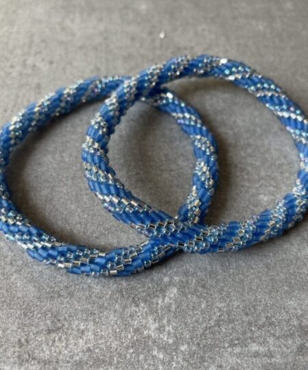 Nepal armbånd er en inspirerende og fascinerende smykkegenre, der vækker interessen hos smykkeentusiaster over hele verden. Disse håndlavede armbånd er kunstværker, der udstråler autenticitet, skønhed og dyb symbolik. Lad os dykke ned i den betagende verden af Nepal armbånd og udforske, hvad der gør dem så unikke og eftertragtede. Hvert Nepal armbånd er unikt, og det er netop denne individualitet, der appellerer til mange. Armbåndene er ofte skabt af dygtige nepalesiske håndværkere, der gennem generationer har forfinet deres teknikker til at skabe smykker af høj kvalitet. Disse håndværkere bruger traditionelle metoder, som har været en del af Nepals kultur og historie i århundreder. Processen er omhyggelig og kræver en stor grad af præcision og tålmodighed, hvilket gør hvert armbånd til en kærlighedsfyldt skabelse. Nepal armbånd er kendt for deres farverige og levende design. De er ofte dekoreret med perler, ædelstene, træ, metal eller andre naturlige materialer, hvilket giver dem et unikt udseende. Hvert enkelt element, der anvendes i armbåndene, er udvalgt omhyggeligt for at skabe en harmonisk kombination af farver og teksturer. Disse elementer er ofte inspireret af Nepals rige natur og kultur, hvilket giver armbåndene en autentisk følelse og en stærk forbindelse til landet. Symbolik spiller også en vigtig rolle i Nepal armbåndenes popularitet. Mange af armbåndene har indgraverede mønstre eller symboler, der repræsenterer vigtige aspekter af Nepals traditioner og spiritualitet. Disse symboler kan have betydning for held, lykke, kærlighed, beskyttelse eller en dybere forbindelse til naturen. At bære et Nepal armbånd kan derfor have en dybere betydning for bæreren og kan fungere som en påmindelse om deres forbindelse til Nepals rige arv. Nepal armbånd er ikke kun smukke smykker, men de har også en stærk social og kulturel betydning. Mange af disse smykker er håndlavede af kvinder, der er en del af samfundet i landområderne i Nepal. Produktionen af armbåndene giver disse kvinder mulighed for at skabe en bæredygtig indkomst, forbedre deres levevilkår og styrke deres selvstændighed. Når du køber et Nepal armbånd, bidrager du derfor til at støtte en positiv social indvirkning og bevare traditionelle håndværksmæssige metoder. Udover deres kulturelle og sociale betydning er Nepal armbånd også en favorit blandt modebevidste enkeltpersoner, der ønsker at tilføje en unik og autentisk touch til deres stil. Disse armbånd kan styles på utallige måder, uanset om du ønsker at skabe et bohemeinspireret look, en farverig festlig stil eller en subtil og elegant kombination. Der er et Nepal armbånd til enhver lejlighed og enhver personlig præference. I det store udvalg af smykker, der findes i dagens marked, skiller Nepal armbånd sig ud som en særlig perle. Deres håndlavede karakter, farverige design, dybe symbolik og sociale indvirkning gør dem til mere end bare smykker - de er en form for kunst og kultur, der fortæller historien om Nepal og dets folk. Ved at bære et Nepal armbånd, bærer du også med dig en del af dette rige og inspirerende land. Så uanset om du leder efter en meningsfuld gave eller ønsker at berige din egen smykkesamling, vil et Nepal armbånd være et mindeværdigt og værdsat valg.