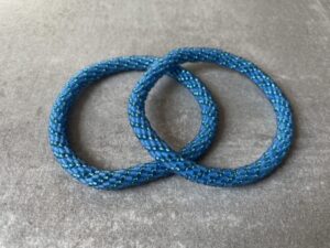 Nepal armbånd er en inspirerende og fascinerende smykkegenre, der vækker interessen hos smykkeentusiaster over hele verden. Disse håndlavede armbånd er kunstværker, der udstråler autenticitet, skønhed og dyb symbolik. Lad os dykke ned i den betagende verden af Nepal armbånd og udforske, hvad der gør dem så unikke og eftertragtede. Hvert Nepal armbånd er unikt, og det er netop denne individualitet, der appellerer til mange. Armbåndene er ofte skabt af dygtige nepalesiske håndværkere, der gennem generationer har forfinet deres teknikker til at skabe smykker af høj kvalitet. Disse håndværkere bruger traditionelle metoder, som har været en del af Nepals kultur og historie i århundreder. Processen er omhyggelig og kræver en stor grad af præcision og tålmodighed, hvilket gør hvert armbånd til en kærlighedsfyldt skabelse. Nepal armbånd er kendt for deres farverige og levende design. De er ofte dekoreret med perler, ædelstene, træ, metal eller andre naturlige materialer, hvilket giver dem et unikt udseende. Hvert enkelt element, der anvendes i armbåndene, er udvalgt omhyggeligt for at skabe en harmonisk kombination af farver og teksturer. Disse elementer er ofte inspireret af Nepals rige natur og kultur, hvilket giver armbåndene en autentisk følelse og en stærk forbindelse til landet. Symbolik spiller også en vigtig rolle i Nepal armbåndenes popularitet. Mange af armbåndene har indgraverede mønstre eller symboler, der repræsenterer vigtige aspekter af Nepals traditioner og spiritualitet. Disse symboler kan have betydning for held, lykke, kærlighed, beskyttelse eller en dybere forbindelse til naturen. At bære et Nepal armbånd kan derfor have en dybere betydning for bæreren og kan fungere som en påmindelse om deres forbindelse til Nepals rige arv. Nepal armbånd er ikke kun smukke smykker, men de har også en stærk social og kulturel betydning. Mange af disse smykker er håndlavede af kvinder, der er en del af samfundet i landområderne i Nepal. Produktionen af armbåndene giver disse kvinder mulighed for at skabe en bæredygtig indkomst, forbedre deres levevilkår og styrke deres selvstændighed. Når du køber et Nepal armbånd, bidrager du derfor til at støtte en positiv social indvirkning og bevare traditionelle håndværksmæssige metoder. Udover deres kulturelle og sociale betydning er Nepal armbånd også en favorit blandt modebevidste enkeltpersoner, der ønsker at tilføje en unik og autentisk touch til deres stil. Disse armbånd kan styles på utallige måder, uanset om du ønsker at skabe et bohemeinspireret look, en farverig festlig stil eller en subtil og elegant kombination. Der er et Nepal armbånd til enhver lejlighed og enhver personlig præference. I det store udvalg af smykker, der findes i dagens marked, skiller Nepal armbånd sig ud som en særlig perle. Deres håndlavede karakter, farverige design, dybe symbolik og sociale indvirkning gør dem til mere end bare smykker - de er en form for kunst og kultur, der fortæller historien om Nepal og dets folk. Ved at bære et Nepal armbånd, bærer du også med dig en del af dette rige og inspirerende land. Så uanset om du leder efter en meningsfuld gave eller ønsker at berige din egen smykkesamling, vil et Nepal armbånd være et mindeværdigt og værdsat valg.
