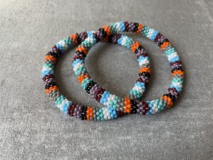 Nepal armbånd er en inspirerende og fascinerende smykkegenre, der vækker interessen hos smykkeentusiaster over hele verden. Disse håndlavede armbånd er kunstværker, der udstråler autenticitet, skønhed og dyb symbolik. Lad os dykke ned i den betagende verden af Nepal armbånd og udforske, hvad der gør dem så unikke og eftertragtede. Hvert Nepal armbånd er unikt, og det er netop denne individualitet, der appellerer til mange. Armbåndene er ofte skabt af dygtige nepalesiske håndværkere, der gennem generationer har forfinet deres teknikker til at skabe smykker af høj kvalitet. Disse håndværkere bruger traditionelle metoder, som har været en del af Nepals kultur og historie i århundreder. Processen er omhyggelig og kræver en stor grad af præcision og tålmodighed, hvilket gør hvert armbånd til en kærlighedsfyldt skabelse. Nepal armbånd er kendt for deres farverige og levende design. De er ofte dekoreret med perler, ædelstene, træ, metal eller andre naturlige materialer, hvilket giver dem et unikt udseende. Hvert enkelt element, der anvendes i armbåndene, er udvalgt omhyggeligt for at skabe en harmonisk kombination af farver og teksturer. Disse elementer er ofte inspireret af Nepals rige natur og kultur, hvilket giver armbåndene en autentisk følelse og en stærk forbindelse til landet. Symbolik spiller også en vigtig rolle i Nepal armbåndenes popularitet. Mange af armbåndene har indgraverede mønstre eller symboler, der repræsenterer vigtige aspekter af Nepals traditioner og spiritualitet. Disse symboler kan have betydning for held, lykke, kærlighed, beskyttelse eller en dybere forbindelse til naturen. At bære et Nepal armbånd kan derfor have en dybere betydning for bæreren og kan fungere som en påmindelse om deres forbindelse til Nepals rige arv. Nepal armbånd er ikke kun smukke smykker, men de har også en stærk social og kulturel betydning. Mange af disse smykker er håndlavede af kvinder, der er en del af samfundet i landområderne i Nepal. Produktionen af armbåndene giver disse kvinder mulighed for at skabe en bæredygtig indkomst, forbedre deres levevilkår og styrke deres selvstændighed. Når du køber et Nepal armbånd, bidrager du derfor til at støtte en positiv social indvirkning og bevare traditionelle håndværksmæssige metoder. Udover deres kulturelle og sociale betydning er Nepal armbånd også en favorit blandt modebevidste enkeltpersoner, der ønsker at tilføje en unik og autentisk touch til deres stil. Disse armbånd kan styles på utallige måder, uanset om du ønsker at skabe et bohemeinspireret look, en farverig festlig stil eller en subtil og elegant kombination. Der er et Nepal armbånd til enhver lejlighed og enhver personlig præference. I det store udvalg af smykker, der findes i dagens marked, skiller Nepal armbånd sig ud som en særlig perle. Deres håndlavede karakter, farverige design, dybe symbolik og sociale indvirkning gør dem til mere end bare smykker - de er en form for kunst og kultur, der fortæller historien om Nepal og dets folk. Ved at bære et Nepal armbånd, bærer du også med dig en del af dette rige og inspirerende land. Så uanset om du leder efter en meningsfuld gave eller ønsker at berige din egen smykkesamling, vil et Nepal armbånd være et mindeværdigt og værdsat valg.