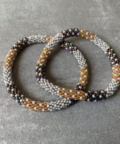 Nepal armbånd er en inspirerende og fascinerende smykkegenre, der vækker interessen hos smykkeentusiaster over hele verden. Disse håndlavede armbånd er kunstværker, der udstråler autenticitet, skønhed og dyb symbolik. Lad os dykke ned i den betagende verden af Nepal armbånd og udforske, hvad der gør dem så unikke og eftertragtede. Hvert Nepal armbånd er unikt, og det er netop denne individualitet, der appellerer til mange. Armbåndene er ofte skabt af dygtige nepalesiske håndværkere, der gennem generationer har forfinet deres teknikker til at skabe smykker af høj kvalitet. Disse håndværkere bruger traditionelle metoder, som har været en del af Nepals kultur og historie i århundreder. Processen er omhyggelig og kræver en stor grad af præcision og tålmodighed, hvilket gør hvert armbånd til en kærlighedsfyldt skabelse. Nepal armbånd er kendt for deres farverige og levende design. De er ofte dekoreret med perler, ædelstene, træ, metal eller andre naturlige materialer, hvilket giver dem et unikt udseende. Hvert enkelt element, der anvendes i armbåndene, er udvalgt omhyggeligt for at skabe en harmonisk kombination af farver og teksturer. Disse elementer er ofte inspireret af Nepals rige natur og kultur, hvilket giver armbåndene en autentisk følelse og en stærk forbindelse til landet. Symbolik spiller også en vigtig rolle i Nepal armbåndenes popularitet. Mange af armbåndene har indgraverede mønstre eller symboler, der repræsenterer vigtige aspekter af Nepals traditioner og spiritualitet. Disse symboler kan have betydning for held, lykke, kærlighed, beskyttelse eller en dybere forbindelse til naturen. At bære et Nepal armbånd kan derfor have en dybere betydning for bæreren og kan fungere som en påmindelse om deres forbindelse til Nepals rige arv. Nepal armbånd er ikke kun smukke smykker, men de har også en stærk social og kulturel betydning. Mange af disse smykker er håndlavede af kvinder, der er en del af samfundet i landområderne i Nepal. Produktionen af armbåndene giver disse kvinder mulighed for at skabe en bæredygtig indkomst, forbedre deres levevilkår og styrke deres selvstændighed. Når du køber et Nepal armbånd, bidrager du derfor til at støtte en positiv social indvirkning og bevare traditionelle håndværksmæssige metoder. Udover deres kulturelle og sociale betydning er Nepal armbånd også en favorit blandt modebevidste enkeltpersoner, der ønsker at tilføje en unik og autentisk touch til deres stil. Disse armbånd kan styles på utallige måder, uanset om du ønsker at skabe et bohemeinspireret look, en farverig festlig stil eller en subtil og elegant kombination. Der er et Nepal armbånd til enhver lejlighed og enhver personlig præference. I det store udvalg af smykker, der findes i dagens marked, skiller Nepal armbånd sig ud som en særlig perle. Deres håndlavede karakter, farverige design, dybe symbolik og sociale indvirkning gør dem til mere end bare smykker - de er en form for kunst og kultur, der fortæller historien om Nepal og dets folk. Ved at bære et Nepal armbånd, bærer du også med dig en del af dette rige og inspirerende land. Så uanset om du leder efter en meningsfuld gave eller ønsker at berige din egen smykkesamling, vil et Nepal armbånd være et mindeværdigt og værdsat valg.