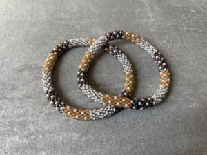 Nepal armbånd er en inspirerende og fascinerende smykkegenre, der vækker interessen hos smykkeentusiaster over hele verden. Disse håndlavede armbånd er kunstværker, der udstråler autenticitet, skønhed og dyb symbolik. Lad os dykke ned i den betagende verden af Nepal armbånd og udforske, hvad der gør dem så unikke og eftertragtede. Hvert Nepal armbånd er unikt, og det er netop denne individualitet, der appellerer til mange. Armbåndene er ofte skabt af dygtige nepalesiske håndværkere, der gennem generationer har forfinet deres teknikker til at skabe smykker af høj kvalitet. Disse håndværkere bruger traditionelle metoder, som har været en del af Nepals kultur og historie i århundreder. Processen er omhyggelig og kræver en stor grad af præcision og tålmodighed, hvilket gør hvert armbånd til en kærlighedsfyldt skabelse. Nepal armbånd er kendt for deres farverige og levende design. De er ofte dekoreret med perler, ædelstene, træ, metal eller andre naturlige materialer, hvilket giver dem et unikt udseende. Hvert enkelt element, der anvendes i armbåndene, er udvalgt omhyggeligt for at skabe en harmonisk kombination af farver og teksturer. Disse elementer er ofte inspireret af Nepals rige natur og kultur, hvilket giver armbåndene en autentisk følelse og en stærk forbindelse til landet. Symbolik spiller også en vigtig rolle i Nepal armbåndenes popularitet. Mange af armbåndene har indgraverede mønstre eller symboler, der repræsenterer vigtige aspekter af Nepals traditioner og spiritualitet. Disse symboler kan have betydning for held, lykke, kærlighed, beskyttelse eller en dybere forbindelse til naturen. At bære et Nepal armbånd kan derfor have en dybere betydning for bæreren og kan fungere som en påmindelse om deres forbindelse til Nepals rige arv. Nepal armbånd er ikke kun smukke smykker, men de har også en stærk social og kulturel betydning. Mange af disse smykker er håndlavede af kvinder, der er en del af samfundet i landområderne i Nepal. Produktionen af armbåndene giver disse kvinder mulighed for at skabe en bæredygtig indkomst, forbedre deres levevilkår og styrke deres selvstændighed. Når du køber et Nepal armbånd, bidrager du derfor til at støtte en positiv social indvirkning og bevare traditionelle håndværksmæssige metoder. Udover deres kulturelle og sociale betydning er Nepal armbånd også en favorit blandt modebevidste enkeltpersoner, der ønsker at tilføje en unik og autentisk touch til deres stil. Disse armbånd kan styles på utallige måder, uanset om du ønsker at skabe et bohemeinspireret look, en farverig festlig stil eller en subtil og elegant kombination. Der er et Nepal armbånd til enhver lejlighed og enhver personlig præference. I det store udvalg af smykker, der findes i dagens marked, skiller Nepal armbånd sig ud som en særlig perle. Deres håndlavede karakter, farverige design, dybe symbolik og sociale indvirkning gør dem til mere end bare smykker - de er en form for kunst og kultur, der fortæller historien om Nepal og dets folk. Ved at bære et Nepal armbånd, bærer du også med dig en del af dette rige og inspirerende land. Så uanset om du leder efter en meningsfuld gave eller ønsker at berige din egen smykkesamling, vil et Nepal armbånd være et mindeværdigt og værdsat valg.