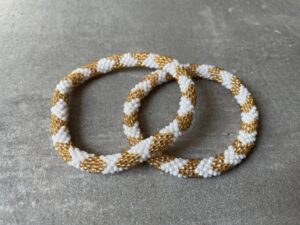 Nepal armbånd er en inspirerende og fascinerende smykkegenre, der vækker interessen hos smykkeentusiaster over hele verden. Disse håndlavede armbånd er kunstværker, der udstråler autenticitet, skønhed og dyb symbolik. Lad os dykke ned i den betagende verden af Nepal armbånd og udforske, hvad der gør dem så unikke og eftertragtede. Hvert Nepal armbånd er unikt, og det er netop denne individualitet, der appellerer til mange. Armbåndene er ofte skabt af dygtige nepalesiske håndværkere, der gennem generationer har forfinet deres teknikker til at skabe smykker af høj kvalitet. Disse håndværkere bruger traditionelle metoder, som har været en del af Nepals kultur og historie i århundreder. Processen er omhyggelig og kræver en stor grad af præcision og tålmodighed, hvilket gør hvert armbånd til en kærlighedsfyldt skabelse. Nepal armbånd er kendt for deres farverige og levende design. De er ofte dekoreret med perler, ædelstene, træ, metal eller andre naturlige materialer, hvilket giver dem et unikt udseende. Hvert enkelt element, der anvendes i armbåndene, er udvalgt omhyggeligt for at skabe en harmonisk kombination af farver og teksturer. Disse elementer er ofte inspireret af Nepals rige natur og kultur, hvilket giver armbåndene en autentisk følelse og en stærk forbindelse til landet. Symbolik spiller også en vigtig rolle i Nepal armbåndenes popularitet. Mange af armbåndene har indgraverede mønstre eller symboler, der repræsenterer vigtige aspekter af Nepals traditioner og spiritualitet. Disse symboler kan have betydning for held, lykke, kærlighed, beskyttelse eller en dybere forbindelse til naturen. At bære et Nepal armbånd kan derfor have en dybere betydning for bæreren og kan fungere som en påmindelse om deres forbindelse til Nepals rige arv. Nepal armbånd er ikke kun smukke smykker, men de har også en stærk social og kulturel betydning. Mange af disse smykker er håndlavede af kvinder, der er en del af samfundet i landområderne i Nepal. Produktionen af armbåndene giver disse kvinder mulighed for at skabe en bæredygtig indkomst, forbedre deres levevilkår og styrke deres selvstændighed. Når du køber et Nepal armbånd, bidrager du derfor til at støtte en positiv social indvirkning og bevare traditionelle håndværksmæssige metoder. Udover deres kulturelle og sociale betydning er Nepal armbånd også en favorit blandt modebevidste enkeltpersoner, der ønsker at tilføje en unik og autentisk touch til deres stil. Disse armbånd kan styles på utallige måder, uanset om du ønsker at skabe et bohemeinspireret look, en farverig festlig stil eller en subtil og elegant kombination. Der er et Nepal armbånd til enhver lejlighed og enhver personlig præference. I det store udvalg af smykker, der findes i dagens marked, skiller Nepal armbånd sig ud som en særlig perle. Deres håndlavede karakter, farverige design, dybe symbolik og sociale indvirkning gør dem til mere end bare smykker - de er en form for kunst og kultur, der fortæller historien om Nepal og dets folk. Ved at bære et Nepal armbånd, bærer du også med dig en del af dette rige og inspirerende land. Så uanset om du leder efter en meningsfuld gave eller ønsker at berige din egen smykkesamling, vil et Nepal armbånd være et mindeværdigt og værdsat valg.