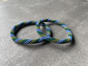 Nepal armbånd er en inspirerende og fascinerende smykkegenre, der vækker interessen hos smykkeentusiaster over hele verden. Disse håndlavede armbånd er kunstværker, der udstråler autenticitet, skønhed og dyb symbolik. Lad os dykke ned i den betagende verden af Nepal armbånd og udforske, hvad der gør dem så unikke og eftertragtede. Hvert Nepal armbånd er unikt, og det er netop denne individualitet, der appellerer til mange. Armbåndene er ofte skabt af dygtige nepalesiske håndværkere, der gennem generationer har forfinet deres teknikker til at skabe smykker af høj kvalitet. Disse håndværkere bruger traditionelle metoder, som har været en del af Nepals kultur og historie i århundreder. Processen er omhyggelig og kræver en stor grad af præcision og tålmodighed, hvilket gør hvert armbånd til en kærlighedsfyldt skabelse. Nepal armbånd er kendt for deres farverige og levende design. De er ofte dekoreret med perler, ædelstene, træ, metal eller andre naturlige materialer, hvilket giver dem et unikt udseende. Hvert enkelt element, der anvendes i armbåndene, er udvalgt omhyggeligt for at skabe en harmonisk kombination af farver og teksturer. Disse elementer er ofte inspireret af Nepals rige natur og kultur, hvilket giver armbåndene en autentisk følelse og en stærk forbindelse til landet. Symbolik spiller også en vigtig rolle i Nepal armbåndenes popularitet. Mange af armbåndene har indgraverede mønstre eller symboler, der repræsenterer vigtige aspekter af Nepals traditioner og spiritualitet. Disse symboler kan have betydning for held, lykke, kærlighed, beskyttelse eller en dybere forbindelse til naturen. At bære et Nepal armbånd kan derfor have en dybere betydning for bæreren og kan fungere som en påmindelse om deres forbindelse til Nepals rige arv. Nepal armbånd er ikke kun smukke smykker, men de har også en stærk social og kulturel betydning. Mange af disse smykker er håndlavede af kvinder, der er en del af samfundet i landområderne i Nepal. Produktionen af armbåndene giver disse kvinder mulighed for at skabe en bæredygtig indkomst, forbedre deres levevilkår og styrke deres selvstændighed. Når du køber et Nepal armbånd, bidrager du derfor til at støtte en positiv social indvirkning og bevare traditionelle håndværksmæssige metoder. Udover deres kulturelle og sociale betydning er Nepal armbånd også en favorit blandt modebevidste enkeltpersoner, der ønsker at tilføje en unik og autentisk touch til deres stil. Disse armbånd kan styles på utallige måder, uanset om du ønsker at skabe et bohemeinspireret look, en farverig festlig stil eller en subtil og elegant kombination. Der er et Nepal armbånd til enhver lejlighed og enhver personlig præference. I det store udvalg af smykker, der findes i dagens marked, skiller Nepal armbånd sig ud som en særlig perle. Deres håndlavede karakter, farverige design, dybe symbolik og sociale indvirkning gør dem til mere end bare smykker - de er en form for kunst og kultur, der fortæller historien om Nepal og dets folk. Ved at bære et Nepal armbånd, bærer du også med dig en del af dette rige og inspirerende land. Så uanset om du leder efter en meningsfuld gave eller ønsker at berige din egen smykkesamling, vil et Nepal armbånd være et mindeværdigt og værdsat valg.