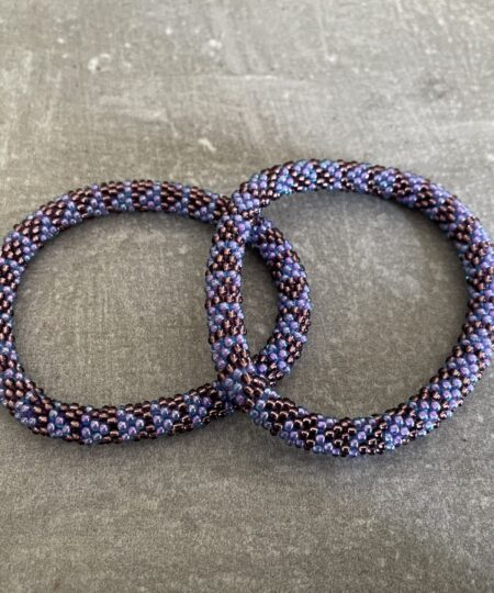 Nepal armbånd er en inspirerende og fascinerende smykkegenre, der vækker interessen hos smykkeentusiaster over hele verden. Disse håndlavede armbånd er kunstværker, der udstråler autenticitet, skønhed og dyb symbolik. Lad os dykke ned i den betagende verden af Nepal armbånd og udforske, hvad der gør dem så unikke og eftertragtede. Hvert Nepal armbånd er unikt, og det er netop denne individualitet, der appellerer til mange. Armbåndene er ofte skabt af dygtige nepalesiske håndværkere, der gennem generationer har forfinet deres teknikker til at skabe smykker af høj kvalitet. Disse håndværkere bruger traditionelle metoder, som har været en del af Nepals kultur og historie i århundreder. Processen er omhyggelig og kræver en stor grad af præcision og tålmodighed, hvilket gør hvert armbånd til en kærlighedsfyldt skabelse. Nepal armbånd er kendt for deres farverige og levende design. De er ofte dekoreret med perler, ædelstene, træ, metal eller andre naturlige materialer, hvilket giver dem et unikt udseende. Hvert enkelt element, der anvendes i armbåndene, er udvalgt omhyggeligt for at skabe en harmonisk kombination af farver og teksturer. Disse elementer er ofte inspireret af Nepals rige natur og kultur, hvilket giver armbåndene en autentisk følelse og en stærk forbindelse til landet. Symbolik spiller også en vigtig rolle i Nepal armbåndenes popularitet. Mange af armbåndene har indgraverede mønstre eller symboler, der repræsenterer vigtige aspekter af Nepals traditioner og spiritualitet. Disse symboler kan have betydning for held, lykke, kærlighed, beskyttelse eller en dybere forbindelse til naturen. At bære et Nepal armbånd kan derfor have en dybere betydning for bæreren og kan fungere som en påmindelse om deres forbindelse til Nepals rige arv. Nepal armbånd er ikke kun smukke smykker, men de har også en stærk social og kulturel betydning. Mange af disse smykker er håndlavede af kvinder, der er en del af samfundet i landområderne i Nepal. Produktionen af armbåndene giver disse kvinder mulighed for at skabe en bæredygtig indkomst, forbedre deres levevilkår og styrke deres selvstændighed. Når du køber et Nepal armbånd, bidrager du derfor til at støtte en positiv social indvirkning og bevare traditionelle håndværksmæssige metoder. Udover deres kulturelle og sociale betydning er Nepal armbånd også en favorit blandt modebevidste enkeltpersoner, der ønsker at tilføje en unik og autentisk touch til deres stil. Disse armbånd kan styles på utallige måder, uanset om du ønsker at skabe et bohemeinspireret look, en farverig festlig stil eller en subtil og elegant kombination. Der er et Nepal armbånd til enhver lejlighed og enhver personlig præference. I det store udvalg af smykker, der findes i dagens marked, skiller Nepal armbånd sig ud som en særlig perle. Deres håndlavede karakter, farverige design, dybe symbolik og sociale indvirkning gør dem til mere end bare smykker - de er en form for kunst og kultur, der fortæller historien om Nepal og dets folk. Ved at bære et Nepal armbånd, bærer du også med dig en del af dette rige og inspirerende land. Så uanset om du leder efter en meningsfuld gave eller ønsker at berige din egen smykkesamling, vil et Nepal armbånd være et mindeværdigt og værdsat valg.