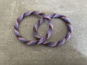 Nepal armbånd er en inspirerende og fascinerende smykkegenre, der vækker interessen hos smykkeentusiaster over hele verden. Disse håndlavede armbånd er kunstværker, der udstråler autenticitet, skønhed og dyb symbolik. Lad os dykke ned i den betagende verden af Nepal armbånd og udforske, hvad der gør dem så unikke og eftertragtede. Hvert Nepal armbånd er unikt, og det er netop denne individualitet, der appellerer til mange. Armbåndene er ofte skabt af dygtige nepalesiske håndværkere, der gennem generationer har forfinet deres teknikker til at skabe smykker af høj kvalitet. Disse håndværkere bruger traditionelle metoder, som har været en del af Nepals kultur og historie i århundreder. Processen er omhyggelig og kræver en stor grad af præcision og tålmodighed, hvilket gør hvert armbånd til en kærlighedsfyldt skabelse. Nepal armbånd er kendt for deres farverige og levende design. De er ofte dekoreret med perler, ædelstene, træ, metal eller andre naturlige materialer, hvilket giver dem et unikt udseende. Hvert enkelt element, der anvendes i armbåndene, er udvalgt omhyggeligt for at skabe en harmonisk kombination af farver og teksturer. Disse elementer er ofte inspireret af Nepals rige natur og kultur, hvilket giver armbåndene en autentisk følelse og en stærk forbindelse til landet. Symbolik spiller også en vigtig rolle i Nepal armbåndenes popularitet. Mange af armbåndene har indgraverede mønstre eller symboler, der repræsenterer vigtige aspekter af Nepals traditioner og spiritualitet. Disse symboler kan have betydning for held, lykke, kærlighed, beskyttelse eller en dybere forbindelse til naturen. At bære et Nepal armbånd kan derfor have en dybere betydning for bæreren og kan fungere som en påmindelse om deres forbindelse til Nepals rige arv. Nepal armbånd er ikke kun smukke smykker, men de har også en stærk social og kulturel betydning. Mange af disse smykker er håndlavede af kvinder, der er en del af samfundet i landområderne i Nepal. Produktionen af armbåndene giver disse kvinder mulighed for at skabe en bæredygtig indkomst, forbedre deres levevilkår og styrke deres selvstændighed. Når du køber et Nepal armbånd, bidrager du derfor til at støtte en positiv social indvirkning og bevare traditionelle håndværksmæssige metoder. Udover deres kulturelle og sociale betydning er Nepal armbånd også en favorit blandt modebevidste enkeltpersoner, der ønsker at tilføje en unik og autentisk touch til deres stil. Disse armbånd kan styles på utallige måder, uanset om du ønsker at skabe et bohemeinspireret look, en farverig festlig stil eller en subtil og elegant kombination. Der er et Nepal armbånd til enhver lejlighed og enhver personlig præference. I det store udvalg af smykker, der findes i dagens marked, skiller Nepal armbånd sig ud som en særlig perle. Deres håndlavede karakter, farverige design, dybe symbolik og sociale indvirkning gør dem til mere end bare smykker - de er en form for kunst og kultur, der fortæller historien om Nepal og dets folk. Ved at bære et Nepal armbånd, bærer du også med dig en del af dette rige og inspirerende land. Så uanset om du leder efter en meningsfuld gave eller ønsker at berige din egen smykkesamling, vil et Nepal armbånd være et mindeværdigt og værdsat valg.