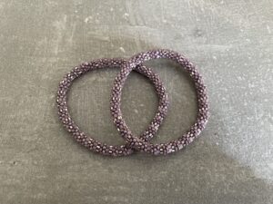 Nepal armbånd er en inspirerende og fascinerende smykkegenre, der vækker interessen hos smykkeentusiaster over hele verden. Disse håndlavede armbånd er kunstværker, der udstråler autenticitet, skønhed og dyb symbolik. Lad os dykke ned i den betagende verden af Nepal armbånd og udforske, hvad der gør dem så unikke og eftertragtede. Hvert Nepal armbånd er unikt, og det er netop denne individualitet, der appellerer til mange. Armbåndene er ofte skabt af dygtige nepalesiske håndværkere, der gennem generationer har forfinet deres teknikker til at skabe smykker af høj kvalitet. Disse håndværkere bruger traditionelle metoder, som har været en del af Nepals kultur og historie i århundreder. Processen er omhyggelig og kræver en stor grad af præcision og tålmodighed, hvilket gør hvert armbånd til en kærlighedsfyldt skabelse. Nepal armbånd er kendt for deres farverige og levende design. De er ofte dekoreret med perler, ædelstene, træ, metal eller andre naturlige materialer, hvilket giver dem et unikt udseende. Hvert enkelt element, der anvendes i armbåndene, er udvalgt omhyggeligt for at skabe en harmonisk kombination af farver og teksturer. Disse elementer er ofte inspireret af Nepals rige natur og kultur, hvilket giver armbåndene en autentisk følelse og en stærk forbindelse til landet. Symbolik spiller også en vigtig rolle i Nepal armbåndenes popularitet. Mange af armbåndene har indgraverede mønstre eller symboler, der repræsenterer vigtige aspekter af Nepals traditioner og spiritualitet. Disse symboler kan have betydning for held, lykke, kærlighed, beskyttelse eller en dybere forbindelse til naturen. At bære et Nepal armbånd kan derfor have en dybere betydning for bæreren og kan fungere som en påmindelse om deres forbindelse til Nepals rige arv. Nepal armbånd er ikke kun smukke smykker, men de har også en stærk social og kulturel betydning. Mange af disse smykker er håndlavede af kvinder, der er en del af samfundet i landområderne i Nepal. Produktionen af armbåndene giver disse kvinder mulighed for at skabe en bæredygtig indkomst, forbedre deres levevilkår og styrke deres selvstændighed. Når du køber et Nepal armbånd, bidrager du derfor til at støtte en positiv social indvirkning og bevare traditionelle håndværksmæssige metoder. Udover deres kulturelle og sociale betydning er Nepal armbånd også en favorit blandt modebevidste enkeltpersoner, der ønsker at tilføje en unik og autentisk touch til deres stil. Disse armbånd kan styles på utallige måder, uanset om du ønsker at skabe et bohemeinspireret look, en farverig festlig stil eller en subtil og elegant kombination. Der er et Nepal armbånd til enhver lejlighed og enhver personlig præference. I det store udvalg af smykker, der findes i dagens marked, skiller Nepal armbånd sig ud som en særlig perle. Deres håndlavede karakter, farverige design, dybe symbolik og sociale indvirkning gør dem til mere end bare smykker - de er en form for kunst og kultur, der fortæller historien om Nepal og dets folk. Ved at bære et Nepal armbånd, bærer du også med dig en del af dette rige og inspirerende land. Så uanset om du leder efter en meningsfuld gave eller ønsker at berige din egen smykkesamling, vil et Nepal armbånd være et mindeværdigt og værdsat valg.