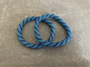 Nepal armbånd er en inspirerende og fascinerende smykkegenre, der vækker interessen hos smykkeentusiaster over hele verden. Disse håndlavede armbånd er kunstværker, der udstråler autenticitet, skønhed og dyb symbolik. Lad os dykke ned i den betagende verden af Nepal armbånd og udforske, hvad der gør dem så unikke og eftertragtede. Hvert Nepal armbånd er unikt, og det er netop denne individualitet, der appellerer til mange. Armbåndene er ofte skabt af dygtige nepalesiske håndværkere, der gennem generationer har forfinet deres teknikker til at skabe smykker af høj kvalitet. Disse håndværkere bruger traditionelle metoder, som har været en del af Nepals kultur og historie i århundreder. Processen er omhyggelig og kræver en stor grad af præcision og tålmodighed, hvilket gør hvert armbånd til en kærlighedsfyldt skabelse. Nepal armbånd er kendt for deres farverige og levende design. De er ofte dekoreret med perler, ædelstene, træ, metal eller andre naturlige materialer, hvilket giver dem et unikt udseende. Hvert enkelt element, der anvendes i armbåndene, er udvalgt omhyggeligt for at skabe en harmonisk kombination af farver og teksturer. Disse elementer er ofte inspireret af Nepals rige natur og kultur, hvilket giver armbåndene en autentisk følelse og en stærk forbindelse til landet. Symbolik spiller også en vigtig rolle i Nepal armbåndenes popularitet. Mange af armbåndene har indgraverede mønstre eller symboler, der repræsenterer vigtige aspekter af Nepals traditioner og spiritualitet. Disse symboler kan have betydning for held, lykke, kærlighed, beskyttelse eller en dybere forbindelse til naturen. At bære et Nepal armbånd kan derfor have en dybere betydning for bæreren og kan fungere som en påmindelse om deres forbindelse til Nepals rige arv. Nepal armbånd er ikke kun smukke smykker, men de har også en stærk social og kulturel betydning. Mange af disse smykker er håndlavede af kvinder, der er en del af samfundet i landområderne i Nepal. Produktionen af armbåndene giver disse kvinder mulighed for at skabe en bæredygtig indkomst, forbedre deres levevilkår og styrke deres selvstændighed. Når du køber et Nepal armbånd, bidrager du derfor til at støtte en positiv social indvirkning og bevare traditionelle håndværksmæssige metoder. Udover deres kulturelle og sociale betydning er Nepal armbånd også en favorit blandt modebevidste enkeltpersoner, der ønsker at tilføje en unik og autentisk touch til deres stil. Disse armbånd kan styles på utallige måder, uanset om du ønsker at skabe et bohemeinspireret look, en farverig festlig stil eller en subtil og elegant kombination. Der er et Nepal armbånd til enhver lejlighed og enhver personlig præference. I det store udvalg af smykker, der findes i dagens marked, skiller Nepal armbånd sig ud som en særlig perle. Deres håndlavede karakter, farverige design, dybe symbolik og sociale indvirkning gør dem til mere end bare smykker - de er en form for kunst og kultur, der fortæller historien om Nepal og dets folk. Ved at bære et Nepal armbånd, bærer du også med dig en del af dette rige og inspirerende land. Så uanset om du leder efter en meningsfuld gave eller ønsker at berige din egen smykkesamling, vil et Nepal armbånd være et mindeværdigt og værdsat valg.