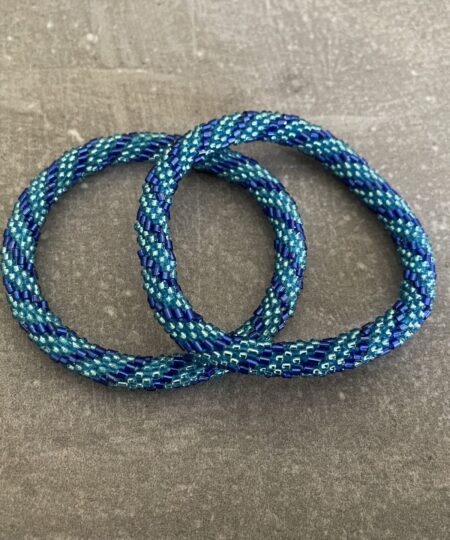 Nepal armbånd er en inspirerende og fascinerende smykkegenre, der vækker interessen hos smykkeentusiaster over hele verden. Disse håndlavede armbånd er kunstværker, der udstråler autenticitet, skønhed og dyb symbolik. Lad os dykke ned i den betagende verden af Nepal armbånd og udforske, hvad der gør dem så unikke og eftertragtede. Hvert Nepal armbånd er unikt, og det er netop denne individualitet, der appellerer til mange. Armbåndene er ofte skabt af dygtige nepalesiske håndværkere, der gennem generationer har forfinet deres teknikker til at skabe smykker af høj kvalitet. Disse håndværkere bruger traditionelle metoder, som har været en del af Nepals kultur og historie i århundreder. Processen er omhyggelig og kræver en stor grad af præcision og tålmodighed, hvilket gør hvert armbånd til en kærlighedsfyldt skabelse. Nepal armbånd er kendt for deres farverige og levende design. De er ofte dekoreret med perler, ædelstene, træ, metal eller andre naturlige materialer, hvilket giver dem et unikt udseende. Hvert enkelt element, der anvendes i armbåndene, er udvalgt omhyggeligt for at skabe en harmonisk kombination af farver og teksturer. Disse elementer er ofte inspireret af Nepals rige natur og kultur, hvilket giver armbåndene en autentisk følelse og en stærk forbindelse til landet. Symbolik spiller også en vigtig rolle i Nepal armbåndenes popularitet. Mange af armbåndene har indgraverede mønstre eller symboler, der repræsenterer vigtige aspekter af Nepals traditioner og spiritualitet. Disse symboler kan have betydning for held, lykke, kærlighed, beskyttelse eller en dybere forbindelse til naturen. At bære et Nepal armbånd kan derfor have en dybere betydning for bæreren og kan fungere som en påmindelse om deres forbindelse til Nepals rige arv. Nepal armbånd er ikke kun smukke smykker, men de har også en stærk social og kulturel betydning. Mange af disse smykker er håndlavede af kvinder, der er en del af samfundet i landområderne i Nepal. Produktionen af armbåndene giver disse kvinder mulighed for at skabe en bæredygtig indkomst, forbedre deres levevilkår og styrke deres selvstændighed. Når du køber et Nepal armbånd, bidrager du derfor til at støtte en positiv social indvirkning og bevare traditionelle håndværksmæssige metoder. Udover deres kulturelle og sociale betydning er Nepal armbånd også en favorit blandt modebevidste enkeltpersoner, der ønsker at tilføje en unik og autentisk touch til deres stil. Disse armbånd kan styles på utallige måder, uanset om du ønsker at skabe et bohemeinspireret look, en farverig festlig stil eller en subtil og elegant kombination. Der er et Nepal armbånd til enhver lejlighed og enhver personlig præference. I det store udvalg af smykker, der findes i dagens marked, skiller Nepal armbånd sig ud som en særlig perle. Deres håndlavede karakter, farverige design, dybe symbolik og sociale indvirkning gør dem til mere end bare smykker - de er en form for kunst og kultur, der fortæller historien om Nepal og dets folk. Ved at bære et Nepal armbånd, bærer du også med dig en del af dette rige og inspirerende land. Så uanset om du leder efter en meningsfuld gave eller ønsker at berige din egen smykkesamling, vil et Nepal armbånd være et mindeværdigt og værdsat valg.