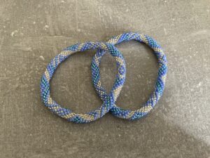 Nepal armbånd er en inspirerende og fascinerende smykkegenre, der vækker interessen hos smykkeentusiaster over hele verden. Disse håndlavede armbånd er kunstværker, der udstråler autenticitet, skønhed og dyb symbolik. Lad os dykke ned i den betagende verden af Nepal armbånd og udforske, hvad der gør dem så unikke og eftertragtede. Hvert Nepal armbånd er unikt, og det er netop denne individualitet, der appellerer til mange. Armbåndene er ofte skabt af dygtige nepalesiske håndværkere, der gennem generationer har forfinet deres teknikker til at skabe smykker af høj kvalitet. Disse håndværkere bruger traditionelle metoder, som har været en del af Nepals kultur og historie i århundreder. Processen er omhyggelig og kræver en stor grad af præcision og tålmodighed, hvilket gør hvert armbånd til en kærlighedsfyldt skabelse. Nepal armbånd er kendt for deres farverige og levende design. De er ofte dekoreret med perler, ædelstene, træ, metal eller andre naturlige materialer, hvilket giver dem et unikt udseende. Hvert enkelt element, der anvendes i armbåndene, er udvalgt omhyggeligt for at skabe en harmonisk kombination af farver og teksturer. Disse elementer er ofte inspireret af Nepals rige natur og kultur, hvilket giver armbåndene en autentisk følelse og en stærk forbindelse til landet. Symbolik spiller også en vigtig rolle i Nepal armbåndenes popularitet. Mange af armbåndene har indgraverede mønstre eller symboler, der repræsenterer vigtige aspekter af Nepals traditioner og spiritualitet. Disse symboler kan have betydning for held, lykke, kærlighed, beskyttelse eller en dybere forbindelse til naturen. At bære et Nepal armbånd kan derfor have en dybere betydning for bæreren og kan fungere som en påmindelse om deres forbindelse til Nepals rige arv. Nepal armbånd er ikke kun smukke smykker, men de har også en stærk social og kulturel betydning. Mange af disse smykker er håndlavede af kvinder, der er en del af samfundet i landområderne i Nepal. Produktionen af armbåndene giver disse kvinder mulighed for at skabe en bæredygtig indkomst, forbedre deres levevilkår og styrke deres selvstændighed. Når du køber et Nepal armbånd, bidrager du derfor til at støtte en positiv social indvirkning og bevare traditionelle håndværksmæssige metoder. Udover deres kulturelle og sociale betydning er Nepal armbånd også en favorit blandt modebevidste enkeltpersoner, der ønsker at tilføje en unik og autentisk touch til deres stil. Disse armbånd kan styles på utallige måder, uanset om du ønsker at skabe et bohemeinspireret look, en farverig festlig stil eller en subtil og elegant kombination. Der er et Nepal armbånd til enhver lejlighed og enhver personlig præference. I det store udvalg af smykker, der findes i dagens marked, skiller Nepal armbånd sig ud som en særlig perle. Deres håndlavede karakter, farverige design, dybe symbolik og sociale indvirkning gør dem til mere end bare smykker - de er en form for kunst og kultur, der fortæller historien om Nepal og dets folk. Ved at bære et Nepal armbånd, bærer du også med dig en del af dette rige og inspirerende land. Så uanset om du leder efter en meningsfuld gave eller ønsker at berige din egen smykkesamling, vil et Nepal armbånd være et mindeværdigt og værdsat valg.