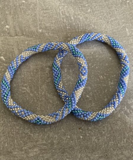 Nepal armbånd er en inspirerende og fascinerende smykkegenre, der vækker interessen hos smykkeentusiaster over hele verden. Disse håndlavede armbånd er kunstværker, der udstråler autenticitet, skønhed og dyb symbolik. Lad os dykke ned i den betagende verden af Nepal armbånd og udforske, hvad der gør dem så unikke og eftertragtede. Hvert Nepal armbånd er unikt, og det er netop denne individualitet, der appellerer til mange. Armbåndene er ofte skabt af dygtige nepalesiske håndværkere, der gennem generationer har forfinet deres teknikker til at skabe smykker af høj kvalitet. Disse håndværkere bruger traditionelle metoder, som har været en del af Nepals kultur og historie i århundreder. Processen er omhyggelig og kræver en stor grad af præcision og tålmodighed, hvilket gør hvert armbånd til en kærlighedsfyldt skabelse. Nepal armbånd er kendt for deres farverige og levende design. De er ofte dekoreret med perler, ædelstene, træ, metal eller andre naturlige materialer, hvilket giver dem et unikt udseende. Hvert enkelt element, der anvendes i armbåndene, er udvalgt omhyggeligt for at skabe en harmonisk kombination af farver og teksturer. Disse elementer er ofte inspireret af Nepals rige natur og kultur, hvilket giver armbåndene en autentisk følelse og en stærk forbindelse til landet. Symbolik spiller også en vigtig rolle i Nepal armbåndenes popularitet. Mange af armbåndene har indgraverede mønstre eller symboler, der repræsenterer vigtige aspekter af Nepals traditioner og spiritualitet. Disse symboler kan have betydning for held, lykke, kærlighed, beskyttelse eller en dybere forbindelse til naturen. At bære et Nepal armbånd kan derfor have en dybere betydning for bæreren og kan fungere som en påmindelse om deres forbindelse til Nepals rige arv. Nepal armbånd er ikke kun smukke smykker, men de har også en stærk social og kulturel betydning. Mange af disse smykker er håndlavede af kvinder, der er en del af samfundet i landområderne i Nepal. Produktionen af armbåndene giver disse kvinder mulighed for at skabe en bæredygtig indkomst, forbedre deres levevilkår og styrke deres selvstændighed. Når du køber et Nepal armbånd, bidrager du derfor til at støtte en positiv social indvirkning og bevare traditionelle håndværksmæssige metoder. Udover deres kulturelle og sociale betydning er Nepal armbånd også en favorit blandt modebevidste enkeltpersoner, der ønsker at tilføje en unik og autentisk touch til deres stil. Disse armbånd kan styles på utallige måder, uanset om du ønsker at skabe et bohemeinspireret look, en farverig festlig stil eller en subtil og elegant kombination. Der er et Nepal armbånd til enhver lejlighed og enhver personlig præference. I det store udvalg af smykker, der findes i dagens marked, skiller Nepal armbånd sig ud som en særlig perle. Deres håndlavede karakter, farverige design, dybe symbolik og sociale indvirkning gør dem til mere end bare smykker - de er en form for kunst og kultur, der fortæller historien om Nepal og dets folk. Ved at bære et Nepal armbånd, bærer du også med dig en del af dette rige og inspirerende land. Så uanset om du leder efter en meningsfuld gave eller ønsker at berige din egen smykkesamling, vil et Nepal armbånd være et mindeværdigt og værdsat valg.