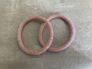 Nepal armbånd er en inspirerende og fascinerende smykkegenre, der vækker interessen hos smykkeentusiaster over hele verden. Disse håndlavede armbånd er kunstværker, der udstråler autenticitet, skønhed og dyb symbolik. Lad os dykke ned i den betagende verden af Nepal armbånd og udforske, hvad der gør dem så unikke og eftertragtede. Hvert Nepal armbånd er unikt, og det er netop denne individualitet, der appellerer til mange. Armbåndene er ofte skabt af dygtige nepalesiske håndværkere, der gennem generationer har forfinet deres teknikker til at skabe smykker af høj kvalitet. Disse håndværkere bruger traditionelle metoder, som har været en del af Nepals kultur og historie i århundreder. Processen er omhyggelig og kræver en stor grad af præcision og tålmodighed, hvilket gør hvert armbånd til en kærlighedsfyldt skabelse. Nepal armbånd er kendt for deres farverige og levende design. De er ofte dekoreret med perler, ædelstene, træ, metal eller andre naturlige materialer, hvilket giver dem et unikt udseende. Hvert enkelt element, der anvendes i armbåndene, er udvalgt omhyggeligt for at skabe en harmonisk kombination af farver og teksturer. Disse elementer er ofte inspireret af Nepals rige natur og kultur, hvilket giver armbåndene en autentisk følelse og en stærk forbindelse til landet. Symbolik spiller også en vigtig rolle i Nepal armbåndenes popularitet. Mange af armbåndene har indgraverede mønstre eller symboler, der repræsenterer vigtige aspekter af Nepals traditioner og spiritualitet. Disse symboler kan have betydning for held, lykke, kærlighed, beskyttelse eller en dybere forbindelse til naturen. At bære et Nepal armbånd kan derfor have en dybere betydning for bæreren og kan fungere som en påmindelse om deres forbindelse til Nepals rige arv. Nepal armbånd er ikke kun smukke smykker, men de har også en stærk social og kulturel betydning. Mange af disse smykker er håndlavede af kvinder, der er en del af samfundet i landområderne i Nepal. Produktionen af armbåndene giver disse kvinder mulighed for at skabe en bæredygtig indkomst, forbedre deres levevilkår og styrke deres selvstændighed. Når du køber et Nepal armbånd, bidrager du derfor til at støtte en positiv social indvirkning og bevare traditionelle håndværksmæssige metoder. Udover deres kulturelle og sociale betydning er Nepal armbånd også en favorit blandt modebevidste enkeltpersoner, der ønsker at tilføje en unik og autentisk touch til deres stil. Disse armbånd kan styles på utallige måder, uanset om du ønsker at skabe et bohemeinspireret look, en farverig festlig stil eller en subtil og elegant kombination. Der er et Nepal armbånd til enhver lejlighed og enhver personlig præference. I det store udvalg af smykker, der findes i dagens marked, skiller Nepal armbånd sig ud som en særlig perle. Deres håndlavede karakter, farverige design, dybe symbolik og sociale indvirkning gør dem til mere end bare smykker - de er en form for kunst og kultur, der fortæller historien om Nepal og dets folk. Ved at bære et Nepal armbånd, bærer du også med dig en del af dette rige og inspirerende land. Så uanset om du leder efter en meningsfuld gave eller ønsker at berige din egen smykkesamling, vil et Nepal armbånd være et mindeværdigt og værdsat valg.
