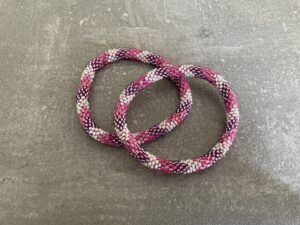 Nepal armbånd er en inspirerende og fascinerende smykkegenre, der vækker interessen hos smykkeentusiaster over hele verden. Disse håndlavede armbånd er kunstværker, der udstråler autenticitet, skønhed og dyb symbolik. Lad os dykke ned i den betagende verden af Nepal armbånd og udforske, hvad der gør dem så unikke og eftertragtede. Hvert Nepal armbånd er unikt, og det er netop denne individualitet, der appellerer til mange. Armbåndene er ofte skabt af dygtige nepalesiske håndværkere, der gennem generationer har forfinet deres teknikker til at skabe smykker af høj kvalitet. Disse håndværkere bruger traditionelle metoder, som har været en del af Nepals kultur og historie i århundreder. Processen er omhyggelig og kræver en stor grad af præcision og tålmodighed, hvilket gør hvert armbånd til en kærlighedsfyldt skabelse. Nepal armbånd er kendt for deres farverige og levende design. De er ofte dekoreret med perler, ædelstene, træ, metal eller andre naturlige materialer, hvilket giver dem et unikt udseende. Hvert enkelt element, der anvendes i armbåndene, er udvalgt omhyggeligt for at skabe en harmonisk kombination af farver og teksturer. Disse elementer er ofte inspireret af Nepals rige natur og kultur, hvilket giver armbåndene en autentisk følelse og en stærk forbindelse til landet. Symbolik spiller også en vigtig rolle i Nepal armbåndenes popularitet. Mange af armbåndene har indgraverede mønstre eller symboler, der repræsenterer vigtige aspekter af Nepals traditioner og spiritualitet. Disse symboler kan have betydning for held, lykke, kærlighed, beskyttelse eller en dybere forbindelse til naturen. At bære et Nepal armbånd kan derfor have en dybere betydning for bæreren og kan fungere som en påmindelse om deres forbindelse til Nepals rige arv. Nepal armbånd er ikke kun smukke smykker, men de har også en stærk social og kulturel betydning. Mange af disse smykker er håndlavede af kvinder, der er en del af samfundet i landområderne i Nepal. Produktionen af armbåndene giver disse kvinder mulighed for at skabe en bæredygtig indkomst, forbedre deres levevilkår og styrke deres selvstændighed. Når du køber et Nepal armbånd, bidrager du derfor til at støtte en positiv social indvirkning og bevare traditionelle håndværksmæssige metoder. Udover deres kulturelle og sociale betydning er Nepal armbånd også en favorit blandt modebevidste enkeltpersoner, der ønsker at tilføje en unik og autentisk touch til deres stil. Disse armbånd kan styles på utallige måder, uanset om du ønsker at skabe et bohemeinspireret look, en farverig festlig stil eller en subtil og elegant kombination. Der er et Nepal armbånd til enhver lejlighed og enhver personlig præference. I det store udvalg af smykker, der findes i dagens marked, skiller Nepal armbånd sig ud som en særlig perle. Deres håndlavede karakter, farverige design, dybe symbolik og sociale indvirkning gør dem til mere end bare smykker - de er en form for kunst og kultur, der fortæller historien om Nepal og dets folk. Ved at bære et Nepal armbånd, bærer du også med dig en del af dette rige og inspirerende land. Så uanset om du leder efter en meningsfuld gave eller ønsker at berige din egen smykkesamling, vil et Nepal armbånd være et mindeværdigt og værdsat valg.