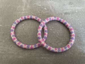 Nepal armbånd er en inspirerende og fascinerende smykkegenre, der vækker interessen hos smykkeentusiaster over hele verden. Disse håndlavede armbånd er kunstværker, der udstråler autenticitet, skønhed og dyb symbolik. Lad os dykke ned i den betagende verden af Nepal armbånd og udforske, hvad der gør dem så unikke og eftertragtede. Hvert Nepal armbånd er unikt, og det er netop denne individualitet, der appellerer til mange. Armbåndene er ofte skabt af dygtige nepalesiske håndværkere, der gennem generationer har forfinet deres teknikker til at skabe smykker af høj kvalitet. Disse håndværkere bruger traditionelle metoder, som har været en del af Nepals kultur og historie i århundreder. Processen er omhyggelig og kræver en stor grad af præcision og tålmodighed, hvilket gør hvert armbånd til en kærlighedsfyldt skabelse. Nepal armbånd er kendt for deres farverige og levende design. De er ofte dekoreret med perler, ædelstene, træ, metal eller andre naturlige materialer, hvilket giver dem et unikt udseende. Hvert enkelt element, der anvendes i armbåndene, er udvalgt omhyggeligt for at skabe en harmonisk kombination af farver og teksturer. Disse elementer er ofte inspireret af Nepals rige natur og kultur, hvilket giver armbåndene en autentisk følelse og en stærk forbindelse til landet. Symbolik spiller også en vigtig rolle i Nepal armbåndenes popularitet. Mange af armbåndene har indgraverede mønstre eller symboler, der repræsenterer vigtige aspekter af Nepals traditioner og spiritualitet. Disse symboler kan have betydning for held, lykke, kærlighed, beskyttelse eller en dybere forbindelse til naturen. At bære et Nepal armbånd kan derfor have en dybere betydning for bæreren og kan fungere som en påmindelse om deres forbindelse til Nepals rige arv. Nepal armbånd er ikke kun smukke smykker, men de har også en stærk social og kulturel betydning. Mange af disse smykker er håndlavede af kvinder, der er en del af samfundet i landområderne i Nepal. Produktionen af armbåndene giver disse kvinder mulighed for at skabe en bæredygtig indkomst, forbedre deres levevilkår og styrke deres selvstændighed. Når du køber et Nepal armbånd, bidrager du derfor til at støtte en positiv social indvirkning og bevare traditionelle håndværksmæssige metoder. Udover deres kulturelle og sociale betydning er Nepal armbånd også en favorit blandt modebevidste enkeltpersoner, der ønsker at tilføje en unik og autentisk touch til deres stil. Disse armbånd kan styles på utallige måder, uanset om du ønsker at skabe et bohemeinspireret look, en farverig festlig stil eller en subtil og elegant kombination. Der er et Nepal armbånd til enhver lejlighed og enhver personlig præference. I det store udvalg af smykker, der findes i dagens marked, skiller Nepal armbånd sig ud som en særlig perle. Deres håndlavede karakter, farverige design, dybe symbolik og sociale indvirkning gør dem til mere end bare smykker - de er en form for kunst og kultur, der fortæller historien om Nepal og dets folk. Ved at bære et Nepal armbånd, bærer du også med dig en del af dette rige og inspirerende land. Så uanset om du leder efter en meningsfuld gave eller ønsker at berige din egen smykkesamling, vil et Nepal armbånd være et mindeværdigt og værdsat valg.