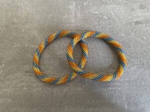 Nepal armbånd er en inspirerende og fascinerende smykkegenre, der vækker interessen hos smykkeentusiaster over hele verden. Disse håndlavede armbånd er kunstværker, der udstråler autenticitet, skønhed og dyb symbolik. Lad os dykke ned i den betagende verden af Nepal armbånd og udforske, hvad der gør dem så unikke og eftertragtede. Hvert Nepal armbånd er unikt, og det er netop denne individualitet, der appellerer til mange. Armbåndene er ofte skabt af dygtige nepalesiske håndværkere, der gennem generationer har forfinet deres teknikker til at skabe smykker af høj kvalitet. Disse håndværkere bruger traditionelle metoder, som har været en del af Nepals kultur og historie i århundreder. Processen er omhyggelig og kræver en stor grad af præcision og tålmodighed, hvilket gør hvert armbånd til en kærlighedsfyldt skabelse. Nepal armbånd er kendt for deres farverige og levende design. De er ofte dekoreret med perler, ædelstene, træ, metal eller andre naturlige materialer, hvilket giver dem et unikt udseende. Hvert enkelt element, der anvendes i armbåndene, er udvalgt omhyggeligt for at skabe en harmonisk kombination af farver og teksturer. Disse elementer er ofte inspireret af Nepals rige natur og kultur, hvilket giver armbåndene en autentisk følelse og en stærk forbindelse til landet. Symbolik spiller også en vigtig rolle i Nepal armbåndenes popularitet. Mange af armbåndene har indgraverede mønstre eller symboler, der repræsenterer vigtige aspekter af Nepals traditioner og spiritualitet. Disse symboler kan have betydning for held, lykke, kærlighed, beskyttelse eller en dybere forbindelse til naturen. At bære et Nepal armbånd kan derfor have en dybere betydning for bæreren og kan fungere som en påmindelse om deres forbindelse til Nepals rige arv. Nepal armbånd er ikke kun smukke smykker, men de har også en stærk social og kulturel betydning. Mange af disse smykker er håndlavede af kvinder, der er en del af samfundet i landområderne i Nepal. Produktionen af armbåndene giver disse kvinder mulighed for at skabe en bæredygtig indkomst, forbedre deres levevilkår og styrke deres selvstændighed. Når du køber et Nepal armbånd, bidrager du derfor til at støtte en positiv social indvirkning og bevare traditionelle håndværksmæssige metoder. Udover deres kulturelle og sociale betydning er Nepal armbånd også en favorit blandt modebevidste enkeltpersoner, der ønsker at tilføje en unik og autentisk touch til deres stil. Disse armbånd kan styles på utallige måder, uanset om du ønsker at skabe et bohemeinspireret look, en farverig festlig stil eller en subtil og elegant kombination. Der er et Nepal armbånd til enhver lejlighed og enhver personlig præference. I det store udvalg af smykker, der findes i dagens marked, skiller Nepal armbånd sig ud som en særlig perle. Deres håndlavede karakter, farverige design, dybe symbolik og sociale indvirkning gør dem til mere end bare smykker - de er en form for kunst og kultur, der fortæller historien om Nepal og dets folk. Ved at bære et Nepal armbånd, bærer du også med dig en del af dette rige og inspirerende land. Så uanset om du leder efter en meningsfuld gave eller ønsker at berige din egen smykkesamling, vil et Nepal armbånd være et mindeværdigt og værdsat valg.
