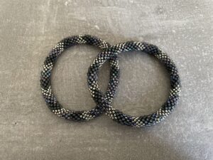 Nepal armbånd er en inspirerende og fascinerende smykkegenre, der vækker interessen hos smykkeentusiaster over hele verden. Disse håndlavede armbånd er kunstværker, der udstråler autenticitet, skønhed og dyb symbolik. Lad os dykke ned i den betagende verden af Nepal armbånd og udforske, hvad der gør dem så unikke og eftertragtede. Hvert Nepal armbånd er unikt, og det er netop denne individualitet, der appellerer til mange. Armbåndene er ofte skabt af dygtige nepalesiske håndværkere, der gennem generationer har forfinet deres teknikker til at skabe smykker af høj kvalitet. Disse håndværkere bruger traditionelle metoder, som har været en del af Nepals kultur og historie i århundreder. Processen er omhyggelig og kræver en stor grad af præcision og tålmodighed, hvilket gør hvert armbånd til en kærlighedsfyldt skabelse. Nepal armbånd er kendt for deres farverige og levende design. De er ofte dekoreret med perler, ædelstene, træ, metal eller andre naturlige materialer, hvilket giver dem et unikt udseende. Hvert enkelt element, der anvendes i armbåndene, er udvalgt omhyggeligt for at skabe en harmonisk kombination af farver og teksturer. Disse elementer er ofte inspireret af Nepals rige natur og kultur, hvilket giver armbåndene en autentisk følelse og en stærk forbindelse til landet. Symbolik spiller også en vigtig rolle i Nepal armbåndenes popularitet. Mange af armbåndene har indgraverede mønstre eller symboler, der repræsenterer vigtige aspekter af Nepals traditioner og spiritualitet. Disse symboler kan have betydning for held, lykke, kærlighed, beskyttelse eller en dybere forbindelse til naturen. At bære et Nepal armbånd kan derfor have en dybere betydning for bæreren og kan fungere som en påmindelse om deres forbindelse til Nepals rige arv. Nepal armbånd er ikke kun smukke smykker, men de har også en stærk social og kulturel betydning. Mange af disse smykker er håndlavede af kvinder, der er en del af samfundet i landområderne i Nepal. Produktionen af armbåndene giver disse kvinder mulighed for at skabe en bæredygtig indkomst, forbedre deres levevilkår og styrke deres selvstændighed. Når du køber et Nepal armbånd, bidrager du derfor til at støtte en positiv social indvirkning og bevare traditionelle håndværksmæssige metoder. Udover deres kulturelle og sociale betydning er Nepal armbånd også en favorit blandt modebevidste enkeltpersoner, der ønsker at tilføje en unik og autentisk touch til deres stil. Disse armbånd kan styles på utallige måder, uanset om du ønsker at skabe et bohemeinspireret look, en farverig festlig stil eller en subtil og elegant kombination. Der er et Nepal armbånd til enhver lejlighed og enhver personlig præference. I det store udvalg af smykker, der findes i dagens marked, skiller Nepal armbånd sig ud som en særlig perle. Deres håndlavede karakter, farverige design, dybe symbolik og sociale indvirkning gør dem til mere end bare smykker - de er en form for kunst og kultur, der fortæller historien om Nepal og dets folk. Ved at bære et Nepal armbånd, bærer du også med dig en del af dette rige og inspirerende land. Så uanset om du leder efter en meningsfuld gave eller ønsker at berige din egen smykkesamling, vil et Nepal armbånd være et mindeværdigt og værdsat valg.