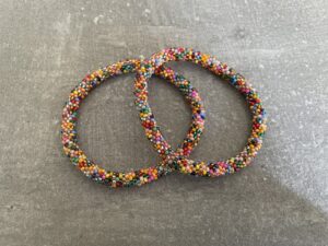 Nepal armbånd er en inspirerende og fascinerende smykkegenre, der vækker interessen hos smykkeentusiaster over hele verden. Disse håndlavede armbånd er kunstværker, der udstråler autenticitet, skønhed og dyb symbolik. Lad os dykke ned i den betagende verden af Nepal armbånd og udforske, hvad der gør dem så unikke og eftertragtede. Hvert Nepal armbånd er unikt, og det er netop denne individualitet, der appellerer til mange. Armbåndene er ofte skabt af dygtige nepalesiske håndværkere, der gennem generationer har forfinet deres teknikker til at skabe smykker af høj kvalitet. Disse håndværkere bruger traditionelle metoder, som har været en del af Nepals kultur og historie i århundreder. Processen er omhyggelig og kræver en stor grad af præcision og tålmodighed, hvilket gør hvert armbånd til en kærlighedsfyldt skabelse. Nepal armbånd er kendt for deres farverige og levende design. De er ofte dekoreret med perler, ædelstene, træ, metal eller andre naturlige materialer, hvilket giver dem et unikt udseende. Hvert enkelt element, der anvendes i armbåndene, er udvalgt omhyggeligt for at skabe en harmonisk kombination af farver og teksturer. Disse elementer er ofte inspireret af Nepals rige natur og kultur, hvilket giver armbåndene en autentisk følelse og en stærk forbindelse til landet. Symbolik spiller også en vigtig rolle i Nepal armbåndenes popularitet. Mange af armbåndene har indgraverede mønstre eller symboler, der repræsenterer vigtige aspekter af Nepals traditioner og spiritualitet. Disse symboler kan have betydning for held, lykke, kærlighed, beskyttelse eller en dybere forbindelse til naturen. At bære et Nepal armbånd kan derfor have en dybere betydning for bæreren og kan fungere som en påmindelse om deres forbindelse til Nepals rige arv. Nepal armbånd er ikke kun smukke smykker, men de har også en stærk social og kulturel betydning. Mange af disse smykker er håndlavede af kvinder, der er en del af samfundet i landområderne i Nepal. Produktionen af armbåndene giver disse kvinder mulighed for at skabe en bæredygtig indkomst, forbedre deres levevilkår og styrke deres selvstændighed. Når du køber et Nepal armbånd, bidrager du derfor til at støtte en positiv social indvirkning og bevare traditionelle håndværksmæssige metoder. Udover deres kulturelle og sociale betydning er Nepal armbånd også en favorit blandt modebevidste enkeltpersoner, der ønsker at tilføje en unik og autentisk touch til deres stil. Disse armbånd kan styles på utallige måder, uanset om du ønsker at skabe et bohemeinspireret look, en farverig festlig stil eller en subtil og elegant kombination. Der er et Nepal armbånd til enhver lejlighed og enhver personlig præference. I det store udvalg af smykker, der findes i dagens marked, skiller Nepal armbånd sig ud som en særlig perle. Deres håndlavede karakter, farverige design, dybe symbolik og sociale indvirkning gør dem til mere end bare smykker - de er en form for kunst og kultur, der fortæller historien om Nepal og dets folk. Ved at bære et Nepal armbånd, bærer du også med dig en del af dette rige og inspirerende land. Så uanset om du leder efter en meningsfuld gave eller ønsker at berige din egen smykkesamling, vil et Nepal armbånd være et mindeværdigt og værdsat valg.
