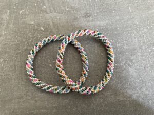 Nepal armbånd er en inspirerende og fascinerende smykkegenre, der vækker interessen hos smykkeentusiaster over hele verden. Disse håndlavede armbånd er kunstværker, der udstråler autenticitet, skønhed og dyb symbolik. Lad os dykke ned i den betagende verden af Nepal armbånd og udforske, hvad der gør dem så unikke og eftertragtede. Hvert Nepal armbånd er unikt, og det er netop denne individualitet, der appellerer til mange. Armbåndene er ofte skabt af dygtige nepalesiske håndværkere, der gennem generationer har forfinet deres teknikker til at skabe smykker af høj kvalitet. Disse håndværkere bruger traditionelle metoder, som har været en del af Nepals kultur og historie i århundreder. Processen er omhyggelig og kræver en stor grad af præcision og tålmodighed, hvilket gør hvert armbånd til en kærlighedsfyldt skabelse. Nepal armbånd er kendt for deres farverige og levende design. De er ofte dekoreret med perler, ædelstene, træ, metal eller andre naturlige materialer, hvilket giver dem et unikt udseende. Hvert enkelt element, der anvendes i armbåndene, er udvalgt omhyggeligt for at skabe en harmonisk kombination af farver og teksturer. Disse elementer er ofte inspireret af Nepals rige natur og kultur, hvilket giver armbåndene en autentisk følelse og en stærk forbindelse til landet. Symbolik spiller også en vigtig rolle i Nepal armbåndenes popularitet. Mange af armbåndene har indgraverede mønstre eller symboler, der repræsenterer vigtige aspekter af Nepals traditioner og spiritualitet. Disse symboler kan have betydning for held, lykke, kærlighed, beskyttelse eller en dybere forbindelse til naturen. At bære et Nepal armbånd kan derfor have en dybere betydning for bæreren og kan fungere som en påmindelse om deres forbindelse til Nepals rige arv. Nepal armbånd er ikke kun smukke smykker, men de har også en stærk social og kulturel betydning. Mange af disse smykker er håndlavede af kvinder, der er en del af samfundet i landområderne i Nepal. Produktionen af armbåndene giver disse kvinder mulighed for at skabe en bæredygtig indkomst, forbedre deres levevilkår og styrke deres selvstændighed. Når du køber et Nepal armbånd, bidrager du derfor til at støtte en positiv social indvirkning og bevare traditionelle håndværksmæssige metoder. Udover deres kulturelle og sociale betydning er Nepal armbånd også en favorit blandt modebevidste enkeltpersoner, der ønsker at tilføje en unik og autentisk touch til deres stil. Disse armbånd kan styles på utallige måder, uanset om du ønsker at skabe et bohemeinspireret look, en farverig festlig stil eller en subtil og elegant kombination. Der er et Nepal armbånd til enhver lejlighed og enhver personlig præference. I det store udvalg af smykker, der findes i dagens marked, skiller Nepal armbånd sig ud som en særlig perle. Deres håndlavede karakter, farverige design, dybe symbolik og sociale indvirkning gør dem til mere end bare smykker - de er en form for kunst og kultur, der fortæller historien om Nepal og dets folk. Ved at bære et Nepal armbånd, bærer du også med dig en del af dette rige og inspirerende land. Så uanset om du leder efter en meningsfuld gave eller ønsker at berige din egen smykkesamling, vil et Nepal armbånd være et mindeværdigt og værdsat valg.
