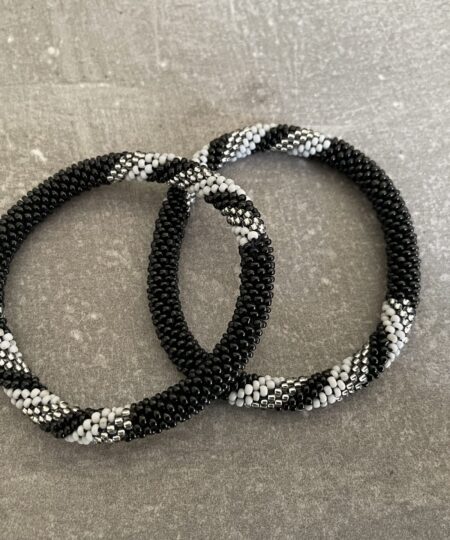 Nepal armbånd er en inspirerende og fascinerende smykkegenre, der vækker interessen hos smykkeentusiaster over hele verden. Disse håndlavede armbånd er kunstværker, der udstråler autenticitet, skønhed og dyb symbolik. Lad os dykke ned i den betagende verden af Nepal armbånd og udforske, hvad der gør dem så unikke og eftertragtede. Hvert Nepal armbånd er unikt, og det er netop denne individualitet, der appellerer til mange. Armbåndene er ofte skabt af dygtige nepalesiske håndværkere, der gennem generationer har forfinet deres teknikker til at skabe smykker af høj kvalitet. Disse håndværkere bruger traditionelle metoder, som har været en del af Nepals kultur og historie i århundreder. Processen er omhyggelig og kræver en stor grad af præcision og tålmodighed, hvilket gør hvert armbånd til en kærlighedsfyldt skabelse. Nepal armbånd er kendt for deres farverige og levende design. De er ofte dekoreret med perler, ædelstene, træ, metal eller andre naturlige materialer, hvilket giver dem et unikt udseende. Hvert enkelt element, der anvendes i armbåndene, er udvalgt omhyggeligt for at skabe en harmonisk kombination af farver og teksturer. Disse elementer er ofte inspireret af Nepals rige natur og kultur, hvilket giver armbåndene en autentisk følelse og en stærk forbindelse til landet. Symbolik spiller også en vigtig rolle i Nepal armbåndenes popularitet. Mange af armbåndene har indgraverede mønstre eller symboler, der repræsenterer vigtige aspekter af Nepals traditioner og spiritualitet. Disse symboler kan have betydning for held, lykke, kærlighed, beskyttelse eller en dybere forbindelse til naturen. At bære et Nepal armbånd kan derfor have en dybere betydning for bæreren og kan fungere som en påmindelse om deres forbindelse til Nepals rige arv. Nepal armbånd er ikke kun smukke smykker, men de har også en stærk social og kulturel betydning. Mange af disse smykker er håndlavede af kvinder, der er en del af samfundet i landområderne i Nepal. Produktionen af armbåndene giver disse kvinder mulighed for at skabe en bæredygtig indkomst, forbedre deres levevilkår og styrke deres selvstændighed. Når du køber et Nepal armbånd, bidrager du derfor til at støtte en positiv social indvirkning og bevare traditionelle håndværksmæssige metoder. Udover deres kulturelle og sociale betydning er Nepal armbånd også en favorit blandt modebevidste enkeltpersoner, der ønsker at tilføje en unik og autentisk touch til deres stil. Disse armbånd kan styles på utallige måder, uanset om du ønsker at skabe et bohemeinspireret look, en farverig festlig stil eller en subtil og elegant kombination. Der er et Nepal armbånd til enhver lejlighed og enhver personlig præference. I det store udvalg af smykker, der findes i dagens marked, skiller Nepal armbånd sig ud som en særlig perle. Deres håndlavede karakter, farverige design, dybe symbolik og sociale indvirkning gør dem til mere end bare smykker - de er en form for kunst og kultur, der fortæller historien om Nepal og dets folk. Ved at bære et Nepal armbånd, bærer du også med dig en del af dette rige og inspirerende land. Så uanset om du leder efter en meningsfuld gave eller ønsker at berige din egen smykkesamling, vil et Nepal armbånd være et mindeværdigt og værdsat valg.