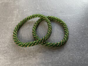 Unikke håndlavet nepal armbånd af glasperler- Som er knyttet perle for perle – Af Nepalesiske Kvinder.  Kvindegrupper i Nepal, Kathmandu Valley, udstyres med glasperler og bomuldsgarn, så de i deres fritid kan håndknytte de smukke perlearmbånd. Hvert armbånd er et unikt resultat af kvindernes håndarbejde og varierer i farvekombinationer og mønstre. De er hæklet med en bomuldssnor. Syntes man at de lidt stramme, kan man vride forsigtigt i dem så de bliver større. syntes man derimod at de er blive lidt for løse, kan man ligge dem i vand. dette gør at bomuldssnoren trækker sig sammen og de bliver mindre igen. Unikke håndlavet nepal armbånd, som er knyttet perle for perle, af nepalesiske kvinder. Vi har mere end 200 forskellige, at vælge i mellem. Så du kan finde de helt rigtige roll on nepal perle armbånd.