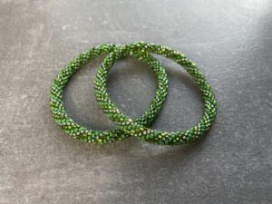 Unikke håndlavet nepal armbånd af glasperler- Som er knyttet perle for perle – Af Nepalesiske Kvinder.  Kvindegrupper i Nepal, Kathmandu Valley, udstyres med glasperler og bomuldsgarn, så de i deres fritid kan håndknytte de smukke perlearmbånd. Hvert armbånd er et unikt resultat af kvindernes håndarbejde og varierer i farvekombinationer og mønstre. De er hæklet med en bomuldssnor. Syntes man at de lidt stramme, kan man vride forsigtigt i dem så de bliver større. syntes man derimod at de er blive lidt for løse, kan man ligge dem i vand. dette gør at bomuldssnoren trækker sig sammen og de bliver mindre igen. Unikke håndlavet nepal armbånd, som er knyttet perle for perle, af nepalesiske kvinder. Vi har mere end 200 forskellige, at vælge i mellem. Så du kan finde de helt rigtige roll on nepal perle armbånd.