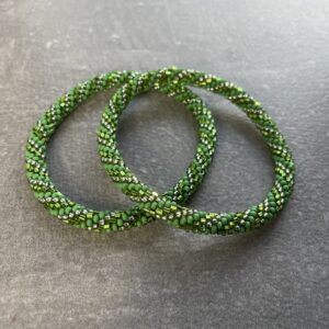 Unikke håndlavet nepal armbånd af glasperler- Som er knyttet perle for perle – Af Nepalesiske Kvinder.  Kvindegrupper i Nepal, Kathmandu Valley, udstyres med glasperler og bomuldsgarn, så de i deres fritid kan håndknytte de smukke perlearmbånd. Hvert armbånd er et unikt resultat af kvindernes håndarbejde og varierer i farvekombinationer og mønstre. De er hæklet med en bomuldssnor. Syntes man at de lidt stramme, kan man vride forsigtigt i dem så de bliver større. syntes man derimod at de er blive lidt for løse, kan man ligge dem i vand. dette gør at bomuldssnoren trækker sig sammen og de bliver mindre igen. Unikke håndlavet nepal armbånd, som er knyttet perle for perle, af nepalesiske kvinder. Vi har mere end 200 forskellige, at vælge i mellem. Så du kan finde de helt rigtige roll on nepal perle armbånd.