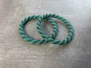 Unikke håndlavet nepal armbånd af glasperler- Som er knyttet perle for perle – Af Nepalesiske Kvinder.  Kvindegrupper i Nepal, Kathmandu Valley, udstyres med glasperler og bomuldsgarn, så de i deres fritid kan håndknytte de smukke perlearmbånd. Hvert armbånd er et unikt resultat af kvindernes håndarbejde og varierer i farvekombinationer og mønstre. De er hæklet med en bomuldssnor. Syntes man at de lidt stramme, kan man vride forsigtigt i dem så de bliver større. syntes man derimod at de er blive lidt for løse, kan man ligge dem i vand. dette gør at bomuldssnoren trækker sig sammen og de bliver mindre igen. Unikke håndlavet nepal armbånd, som er knyttet perle for perle, af nepalesiske kvinder. Vi har mere end 200 forskellige, at vælge i mellem. Så du kan finde de helt rigtige roll on nepal perle armbånd.