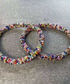 Unikke håndlavet nepal armbånd af glasperler- Som er knyttet perle for perle – Af Nepalesiske Kvinder.  Kvindegrupper i Nepal, Kathmandu Valley, udstyres med glasperler og bomuldsgarn, så de i deres fritid kan håndknytte de smukke perlearmbånd. Hvert armbånd er et unikt resultat af kvindernes håndarbejde og varierer i farvekombinationer og mønstre. De er hæklet med en bomuldssnor. Syntes man at de lidt stramme, kan man vride forsigtigt i dem så de bliver større. syntes man derimod at de er blive lidt for løse, kan man ligge dem i vand. dette gør at bomuldssnoren trækker sig sammen og de bliver mindre igen. Unikke håndlavet nepal armbånd, som er knyttet perle for perle, af nepalesiske kvinder. Vi har mere end 200 forskellige, at vælge i mellem. Så du kan finde de helt rigtige roll on nepal perle armbånd.