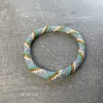 Unikke håndlavet nepal armbånd af glasperler- Som er knyttet perle for perle – Af Nepalesiske Kvinder.  Kvindegrupper i Nepal, Kathmandu Valley, udstyres med glasperler og bomuldsgarn, så de i deres fritid kan håndknytte de smukke perlearmbånd. Hvert armbånd er et unikt resultat af kvindernes håndarbejde og varierer i farvekombinationer og mønstre. De er hæklet med en bomuldssnor. Syntes man at de lidt stramme, kan man vride forsigtigt i dem så de bliver større. syntes man derimod at de er blive lidt for løse, kan man ligge dem i vand. dette gør at bomuldssnoren trækker sig sammen og de bliver mindre igen. Unikke håndlavet nepal armbånd, som er knyttet perle for perle, af nepalesiske kvinder. Vi har mere end 200 forskellige, at vælge i mellem. Så du kan finde de helt rigtige roll on nepal perle armbånd.