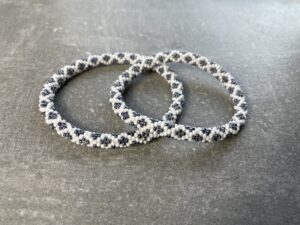 Unikke håndlavet nepal armbånd af glasperler- Som er knyttet perle for perle – Af Nepalesiske Kvinder.  Kvindegrupper i Nepal, Kathmandu Valley, udstyres med glasperler og bomuldsgarn, så de i deres fritid kan håndknytte de smukke perlearmbånd. Hvert armbånd er et unikt resultat af kvindernes håndarbejde og varierer i farvekombinationer og mønstre. De er hæklet med en bomuldssnor. Syntes man at de lidt stramme, kan man vride forsigtigt i dem så de bliver større. syntes man derimod at de er blive lidt for løse, kan man ligge dem i vand. dette gør at bomuldssnoren trækker sig sammen og de bliver mindre igen. Unikke håndlavet nepal armbånd, som er knyttet perle for perle, af nepalesiske kvinder. Vi har mere end 200 forskellige, at vælge i mellem. Så du kan finde de helt rigtige roll on nepal perle armbånd.