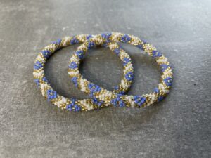 Unikke håndlavet nepal armbånd af glasperler- Som er knyttet perle for perle – Af Nepalesiske Kvinder.  Kvindegrupper i Nepal, Kathmandu Valley, udstyres med glasperler og bomuldsgarn, så de i deres fritid kan håndknytte de smukke perlearmbånd. Hvert armbånd er et unikt resultat af kvindernes håndarbejde og varierer i farvekombinationer og mønstre. De er hæklet med en bomuldssnor. Syntes man at de lidt stramme, kan man vride forsigtigt i dem så de bliver større. syntes man derimod at de er blive lidt for løse, kan man ligge dem i vand. dette gør at bomuldssnoren trækker sig sammen og de bliver mindre igen. Unikke håndlavet nepal armbånd, som er knyttet perle for perle, af nepalesiske kvinder. Vi har mere end 200 forskellige, at vælge i mellem. Så du kan finde de helt rigtige roll on nepal perle armbånd.