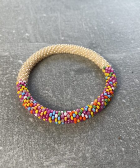 Unikke håndlavet nepal armbånd af glasperler- Som er knyttet perle for perle – Af Nepalesiske Kvinder.  Kvindegrupper i Nepal, Kathmandu Valley, udstyres med glasperler og bomuldsgarn, så de i deres fritid kan håndknytte de smukke perlearmbånd. Hvert armbånd er et unikt resultat af kvindernes håndarbejde og varierer i farvekombinationer og mønstre. De er hæklet med en bomuldssnor. Syntes man at de lidt stramme, kan man vride forsigtigt i dem så de bliver større. syntes man derimod at de er blive lidt for løse, kan man ligge dem i vand. dette gør at bomuldssnoren trækker sig sammen og de bliver mindre igen. Unikke håndlavet nepal armbånd, som er knyttet perle for perle, af nepalesiske kvinder. Vi har mere end 200 forskellige, at vælge i mellem. Så du kan finde de helt rigtige roll on nepal perle armbånd.