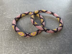Unikke håndlavet nepal armbånd af glasperler- Som er knyttet perle for perle – Af Nepalesiske Kvinder.  Kvindegrupper i Nepal, Kathmandu Valley, udstyres med glasperler og bomuldsgarn, så de i deres fritid kan håndknytte de smukke perlearmbånd. Hvert armbånd er et unikt resultat af kvindernes håndarbejde og varierer i farvekombinationer og mønstre. De er hæklet med en bomuldssnor. Syntes man at de lidt stramme, kan man vride forsigtigt i dem så de bliver større. syntes man derimod at de er blive lidt for løse, kan man ligge dem i vand. dette gør at bomuldssnoren trækker sig sammen og de bliver mindre igen. Unikke håndlavet nepal armbånd, som er knyttet perle for perle, af nepalesiske kvinder. Vi har mere end 200 forskellige, at vælge i mellem. Så du kan finde de helt rigtige roll on nepal perle armbånd.