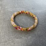 Unikke håndlavet nepal armbånd af glasperler- Som er knyttet perle for perle – Af Nepalesiske Kvinder.  Kvindegrupper i Nepal, Kathmandu Valley, udstyres med glasperler og bomuldsgarn, så de i deres fritid kan håndknytte de smukke perlearmbånd. Hvert armbånd er et unikt resultat af kvindernes håndarbejde og varierer i farvekombinationer og mønstre. De er hæklet med en bomuldssnor. Syntes man at de lidt stramme, kan man vride forsigtigt i dem så de bliver større. syntes man derimod at de er blive lidt for løse, kan man ligge dem i vand. dette gør at bomuldssnoren trækker sig sammen og de bliver mindre igen. Unikke håndlavet nepal armbånd, som er knyttet perle for perle, af nepalesiske kvinder. Vi har mere end 200 forskellige, at vælge i mellem. Så du kan finde de helt rigtige roll on nepal perle armbånd.