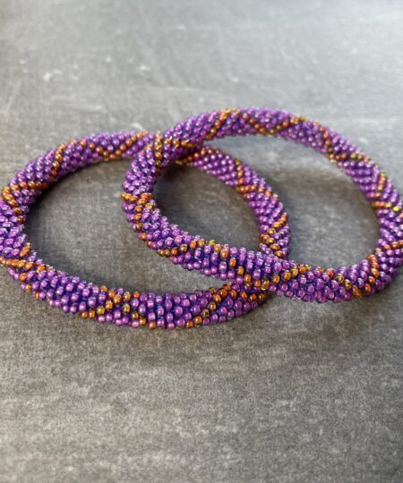 Unikke håndlavet nepal armbånd af glasperler- Som er knyttet perle for perle – Af Nepalesiske Kvinder.  Kvindegrupper i Nepal, Kathmandu Valley, udstyres med glasperler og bomuldsgarn, så de i deres fritid kan håndknytte de smukke perlearmbånd. Hvert armbånd er et unikt resultat af kvindernes håndarbejde og varierer i farvekombinationer og mønstre. De er hæklet med en bomuldssnor. Syntes man at de lidt stramme, kan man vride forsigtigt i dem så de bliver større. syntes man derimod at de er blive lidt for løse, kan man ligge dem i vand. dette gør at bomuldssnoren trækker sig sammen og de bliver mindre igen. Unikke håndlavet nepal armbånd, som er knyttet perle for perle, af nepalesiske kvinder. Vi har mere end 200 forskellige, at vælge i mellem. Så du kan finde de helt rigtige roll on nepal perle armbånd.