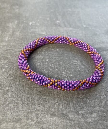 Unikke håndlavet nepal armbånd af glasperler- Som er knyttet perle for perle – Af Nepalesiske Kvinder.  Kvindegrupper i Nepal, Kathmandu Valley, udstyres med glasperler og bomuldsgarn, så de i deres fritid kan håndknytte de smukke perlearmbånd. Hvert armbånd er et unikt resultat af kvindernes håndarbejde og varierer i farvekombinationer og mønstre. De er hæklet med en bomuldssnor. Syntes man at de lidt stramme, kan man vride forsigtigt i dem så de bliver større. syntes man derimod at de er blive lidt for løse, kan man ligge dem i vand. dette gør at bomuldssnoren trækker sig sammen og de bliver mindre igen. Unikke håndlavet nepal armbånd, som er knyttet perle for perle, af nepalesiske kvinder. Vi har mere end 200 forskellige, at vælge i mellem. Så du kan finde de helt rigtige roll on nepal perle armbånd.