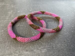 Unikke håndlavet nepal armbånd af glasperler- Som er knyttet perle for perle – Af Nepalesiske Kvinder.  Kvindegrupper i Nepal, Kathmandu Valley, udstyres med glasperler og bomuldsgarn, så de i deres fritid kan håndknytte de smukke perlearmbånd. Hvert armbånd er et unikt resultat af kvindernes håndarbejde og varierer i farvekombinationer og mønstre. De er hæklet med en bomuldssnor. Syntes man at de lidt stramme, kan man vride forsigtigt i dem så de bliver større. syntes man derimod at de er blive lidt for løse, kan man ligge dem i vand. dette gør at bomuldssnoren trækker sig sammen og de bliver mindre igen. Unikke håndlavet nepal armbånd, som er knyttet perle for perle, af nepalesiske kvinder. Vi har mere end 200 forskellige, at vælge i mellem. Så du kan finde de helt rigtige roll on nepal perle armbånd.