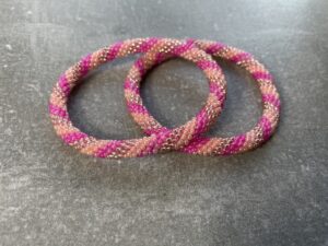 Unikke håndlavet nepal armbånd af glasperler- Som er knyttet perle for perle – Af Nepalesiske Kvinder.  Kvindegrupper i Nepal, Kathmandu Valley, udstyres med glasperler og bomuldsgarn, så de i deres fritid kan håndknytte de smukke perlearmbånd. Hvert armbånd er et unikt resultat af kvindernes håndarbejde og varierer i farvekombinationer og mønstre. De er hæklet med en bomuldssnor. Syntes man at de lidt stramme, kan man vride forsigtigt i dem så de bliver større. syntes man derimod at de er blive lidt for løse, kan man ligge dem i vand. dette gør at bomuldssnoren trækker sig sammen og de bliver mindre igen. Unikke håndlavet nepal armbånd, som er knyttet perle for perle, af nepalesiske kvinder. Vi har mere end 200 forskellige, at vælge i mellem. Så du kan finde de helt rigtige roll on nepal perle armbånd.