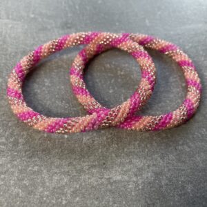 Unikke håndlavet nepal armbånd af glasperler- Som er knyttet perle for perle – Af Nepalesiske Kvinder.  Kvindegrupper i Nepal, Kathmandu Valley, udstyres med glasperler og bomuldsgarn, så de i deres fritid kan håndknytte de smukke perlearmbånd. Hvert armbånd er et unikt resultat af kvindernes håndarbejde og varierer i farvekombinationer og mønstre. De er hæklet med en bomuldssnor. Syntes man at de lidt stramme, kan man vride forsigtigt i dem så de bliver større. syntes man derimod at de er blive lidt for løse, kan man ligge dem i vand. dette gør at bomuldssnoren trækker sig sammen og de bliver mindre igen. Unikke håndlavet nepal armbånd, som er knyttet perle for perle, af nepalesiske kvinder. Vi har mere end 200 forskellige, at vælge i mellem. Så du kan finde de helt rigtige roll on nepal perle armbånd.