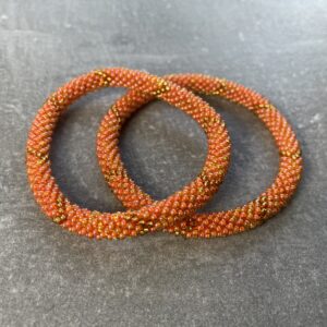 Unikke håndlavet nepal armbånd af glasperler- Som er knyttet perle for perle – Af Nepalesiske Kvinder.  Kvindegrupper i Nepal, Kathmandu Valley, udstyres med glasperler og bomuldsgarn, så de i deres fritid kan håndknytte de smukke perlearmbånd. Hvert armbånd er et unikt resultat af kvindernes håndarbejde og varierer i farvekombinationer og mønstre. De er hæklet med en bomuldssnor. Syntes man at de lidt stramme, kan man vride forsigtigt i dem så de bliver større. syntes man derimod at de er blive lidt for løse, kan man ligge dem i vand. dette gør at bomuldssnoren trækker sig sammen og de bliver mindre igen. Unikke håndlavet nepal armbånd, som er knyttet perle for perle, af nepalesiske kvinder. Vi har mere end 200 forskellige, at vælge i mellem. Så du kan finde de helt rigtige roll on nepal perle armbånd.