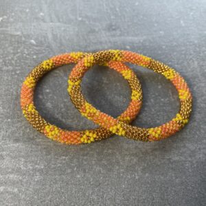 Unikke håndlavet nepal armbånd af glasperler- Som er knyttet perle for perle – Af Nepalesiske Kvinder.  Kvindegrupper i Nepal, Kathmandu Valley, udstyres med glasperler og bomuldsgarn, så de i deres fritid kan håndknytte de smukke perlearmbånd. Hvert armbånd er et unikt resultat af kvindernes håndarbejde og varierer i farvekombinationer og mønstre. De er hæklet med en bomuldssnor. Syntes man at de lidt stramme, kan man vride forsigtigt i dem så de bliver større. syntes man derimod at de er blive lidt for løse, kan man ligge dem i vand. dette gør at bomuldssnoren trækker sig sammen og de bliver mindre igen. Unikke håndlavet nepal armbånd, som er knyttet perle for perle, af nepalesiske kvinder. Vi har mere end 200 forskellige, at vælge i mellem. Så du kan finde de helt rigtige roll on nepal perle armbånd.