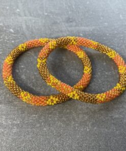 Unikke håndlavet nepal armbånd af glasperler- Som er knyttet perle for perle – Af Nepalesiske Kvinder. Kvindegrupper i Nepal, Kathmandu Valley, udstyres med glasperler og bomuldsgarn, så de i deres fritid kan håndknytte de smukke perlearmbånd. Hvert armbånd er et unikt resultat af kvindernes håndarbejde og varierer i farvekombinationer og mønstre. De er hæklet med en bomuldssnor. Syntes man at de lidt stramme, kan man vride forsigtigt i dem så de bliver større. syntes man derimod at de er blive lidt for løse, kan man ligge dem i vand. dette gør at bomuldssnoren trækker sig sammen og de bliver mindre igen. Unikke håndlavet nepal armbånd, som er knyttet perle for perle, af nepalesiske kvinder. Vi har mere end 200 forskellige, at vælge i mellem. Så du kan finde de helt rigtige roll on nepal perle armbånd.