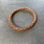 Unikke håndlavet nepal armbånd af glasperler- Som er knyttet perle for perle – Af Nepalesiske Kvinder.  Kvindegrupper i Nepal, Kathmandu Valley, udstyres med glasperler og bomuldsgarn, så de i deres fritid kan håndknytte de smukke perlearmbånd. Hvert armbånd er et unikt resultat af kvindernes håndarbejde og varierer i farvekombinationer og mønstre. De er hæklet med en bomuldssnor. Syntes man at de lidt stramme, kan man vride forsigtigt i dem så de bliver større. syntes man derimod at de er blive lidt for løse, kan man ligge dem i vand. dette gør at bomuldssnoren trækker sig sammen og de bliver mindre igen. Unikke håndlavet nepal armbånd, som er knyttet perle for perle, af nepalesiske kvinder. Vi har mere end 200 forskellige, at vælge i mellem. Så du kan finde de helt rigtige roll on nepal perle armbånd.