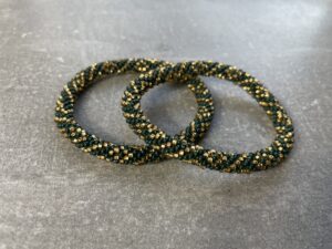 Unikke håndlavet nepal armbånd af glasperler- Som er knyttet perle for perle – Af Nepalesiske Kvinder.  Kvindegrupper i Nepal, Kathmandu Valley, udstyres med glasperler og bomuldsgarn, så de i deres fritid kan håndknytte de smukke perlearmbånd. Hvert armbånd er et unikt resultat af kvindernes håndarbejde og varierer i farvekombinationer og mønstre. De er hæklet med en bomuldssnor. Syntes man at de lidt stramme, kan man vride forsigtigt i dem så de bliver større. syntes man derimod at de er blive lidt for løse, kan man ligge dem i vand. dette gør at bomuldssnoren trækker sig sammen og de bliver mindre igen. Unikke håndlavet nepal armbånd, som er knyttet perle for perle, af nepalesiske kvinder. Vi har mere end 200 forskellige, at vælge i mellem. Så du kan finde de helt rigtige roll on nepal perle armbånd.