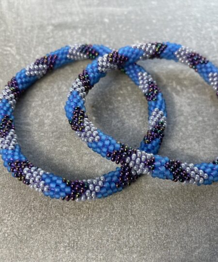 Unikke håndlavet nepal armbånd af glasperler- Som er knyttet perle for perle – Af Nepalesiske Kvinder.  Kvindegrupper i Nepal, Kathmandu Valley, udstyres med glasperler og bomuldsgarn, så de i deres fritid kan håndknytte de smukke perlearmbånd. Hvert armbånd er et unikt resultat af kvindernes håndarbejde og varierer i farvekombinationer og mønstre. De er hæklet med en bomuldssnor. Syntes man at de lidt stramme, kan man vride forsigtigt i dem så de bliver større. syntes man derimod at de er blive lidt for løse, kan man ligge dem i vand. dette gør at bomuldssnoren trækker sig sammen og de bliver mindre igen. Unikke håndlavet nepal armbånd, som er knyttet perle for perle, af nepalesiske kvinder. Vi har mere end 200 forskellige, at vælge i mellem. Så du kan finde de helt rigtige roll on nepal perle armbånd.